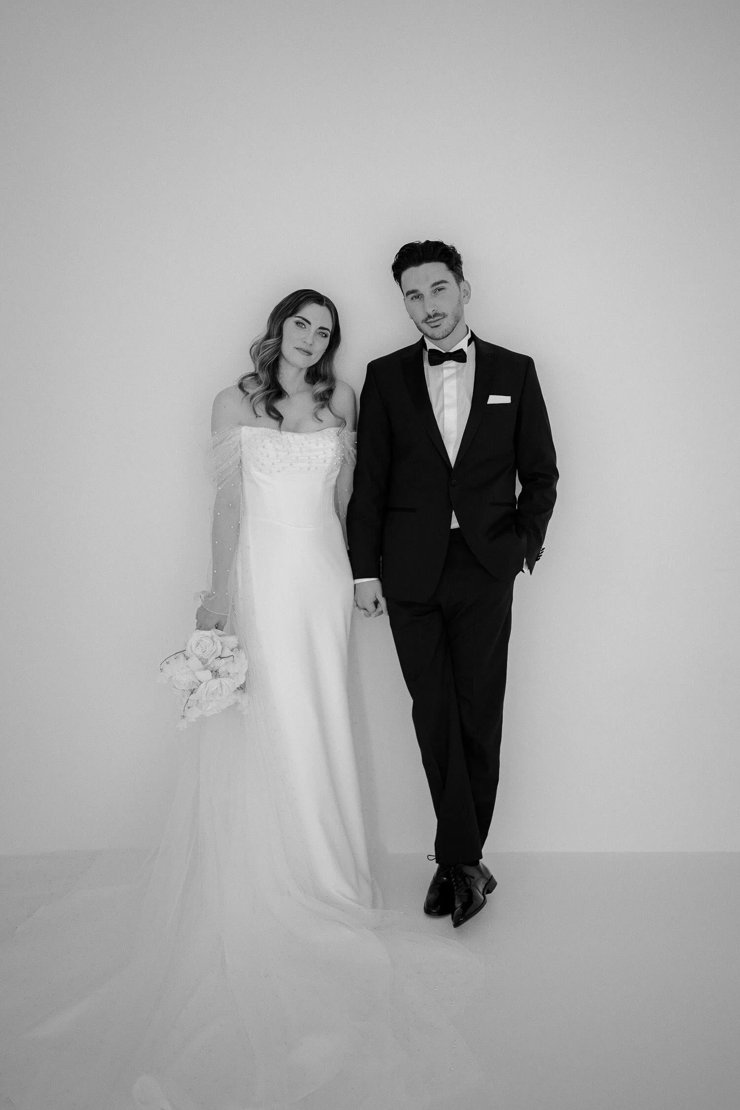 Braut und Bräutigam schauen lässig in die Kamera in einem Studio bei Augsburg.