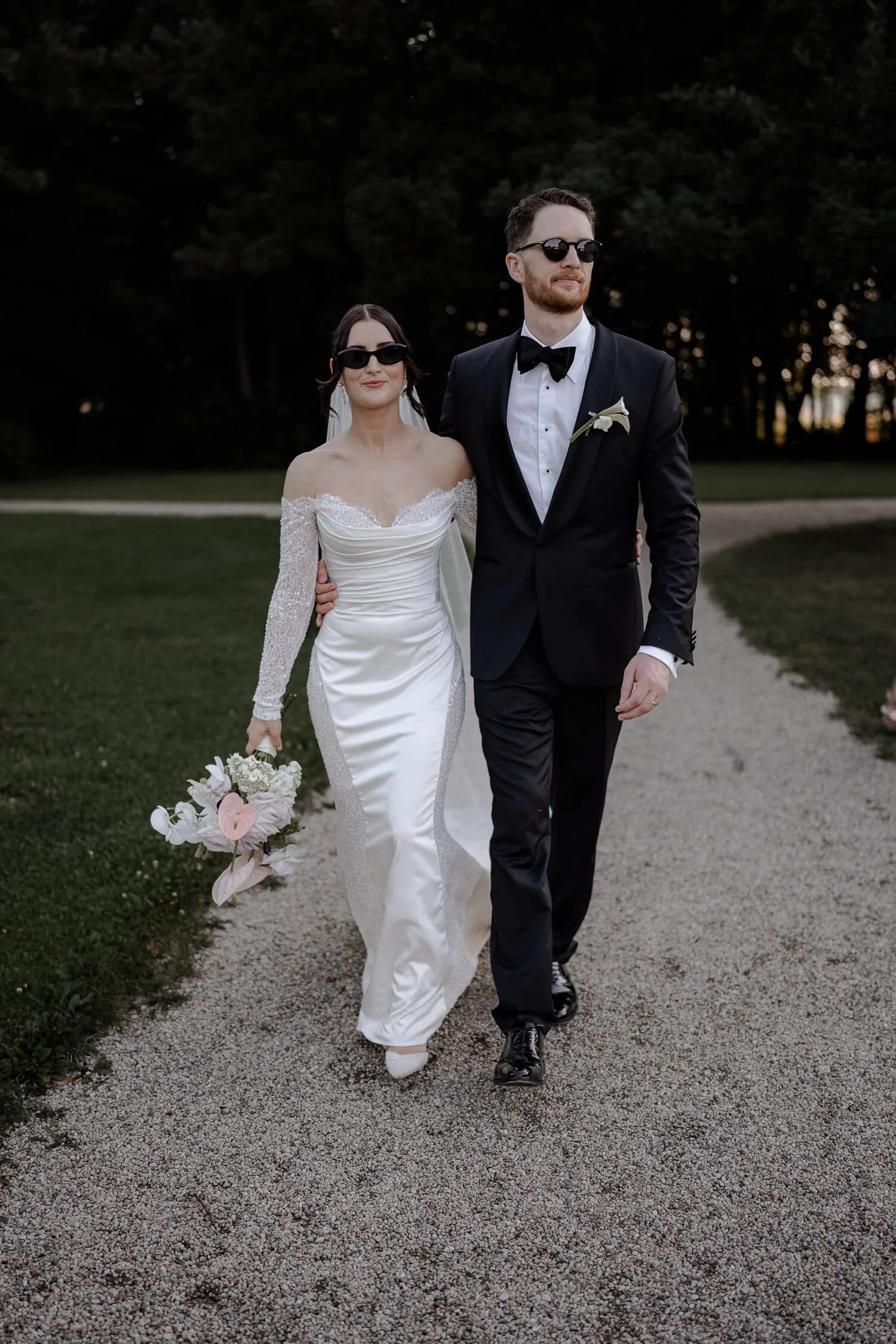 Stilvolles Brautpaar mit Sonnenbrillen bei Hochzeit.