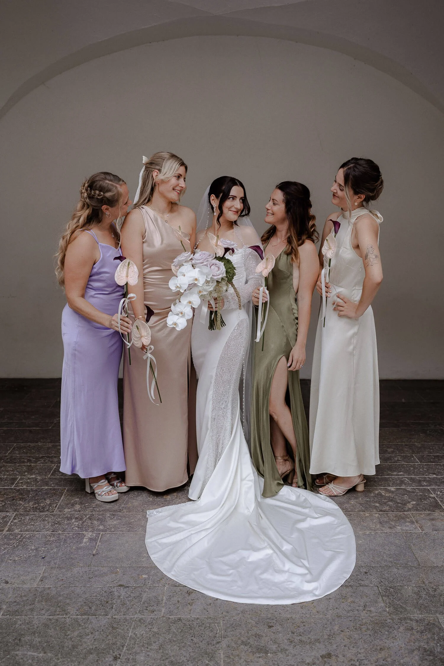 Glückliche Braut in Schloss Hohenkammer mit ihren Brautjungfern in eleganten Kleidern und pastellfarbenen Blumen.
