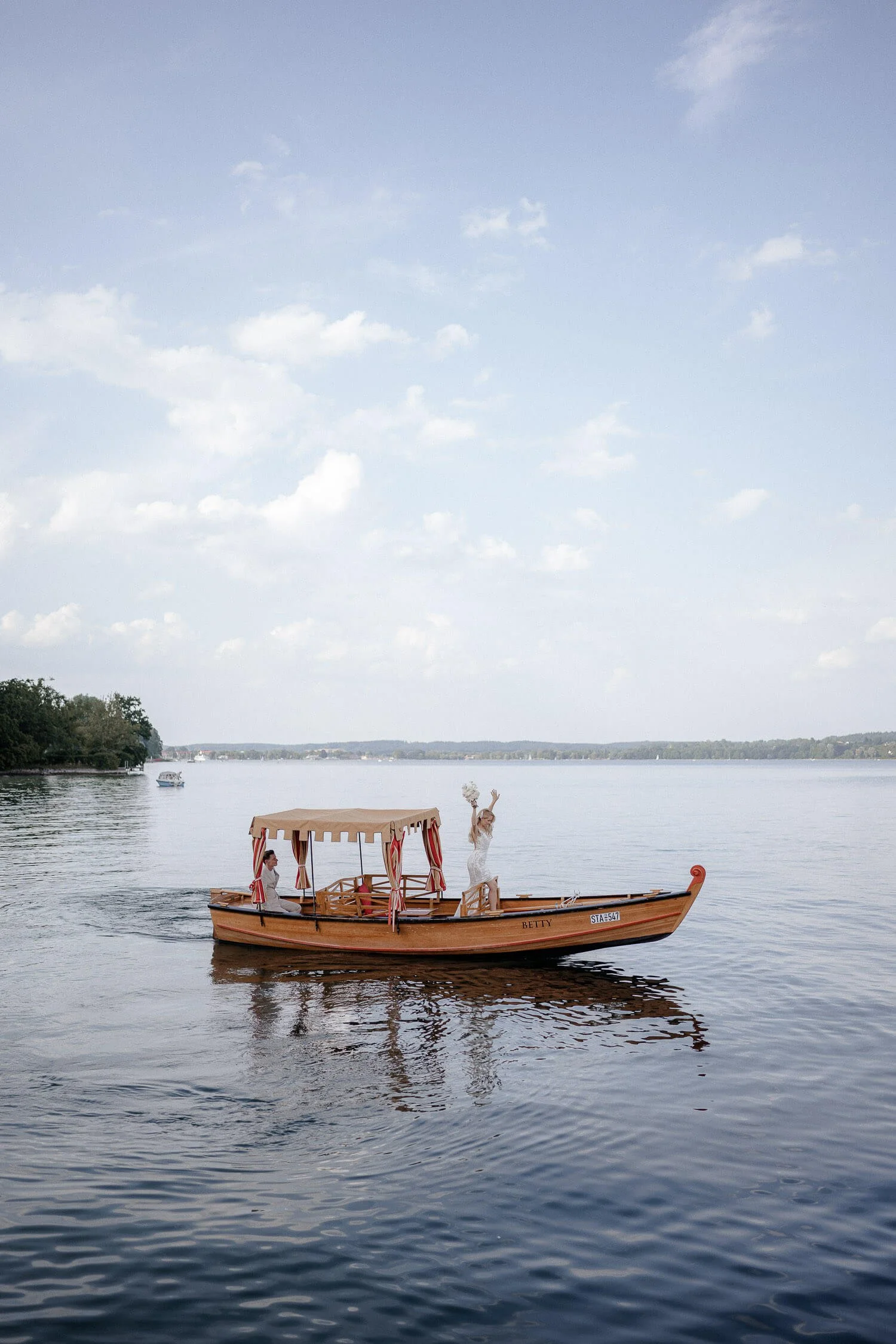 Braut winkt vom Boot auf dem Starnberger See bei Hochzeit