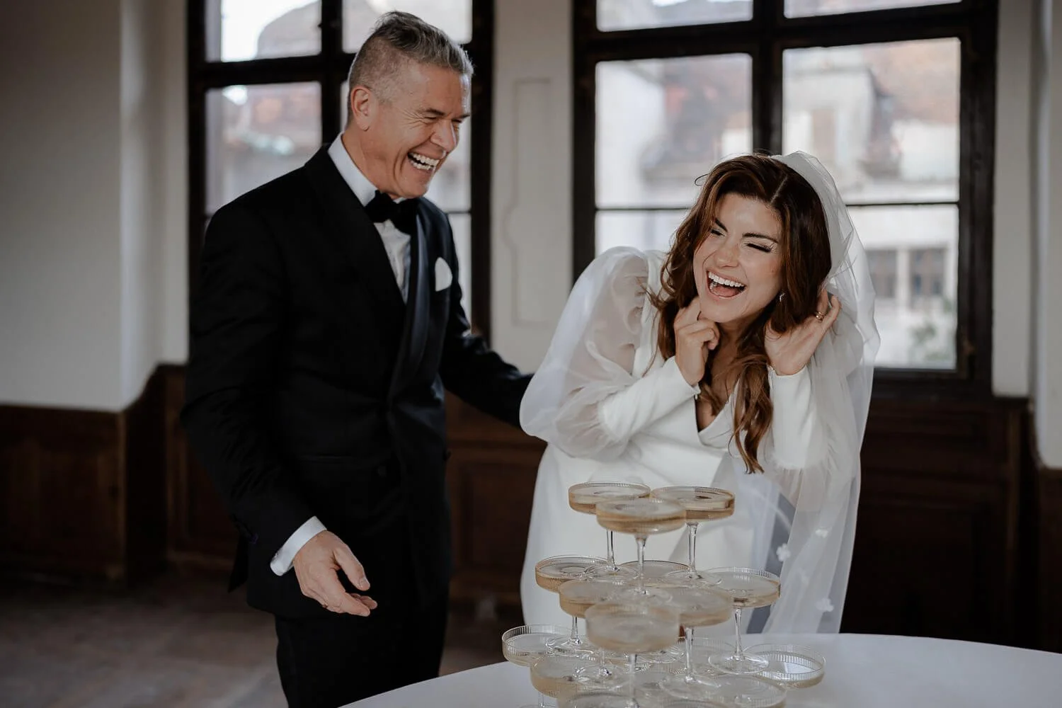 Brautpaar lacht am Champagner-Turm – professioneller Hochzeitsfotograf