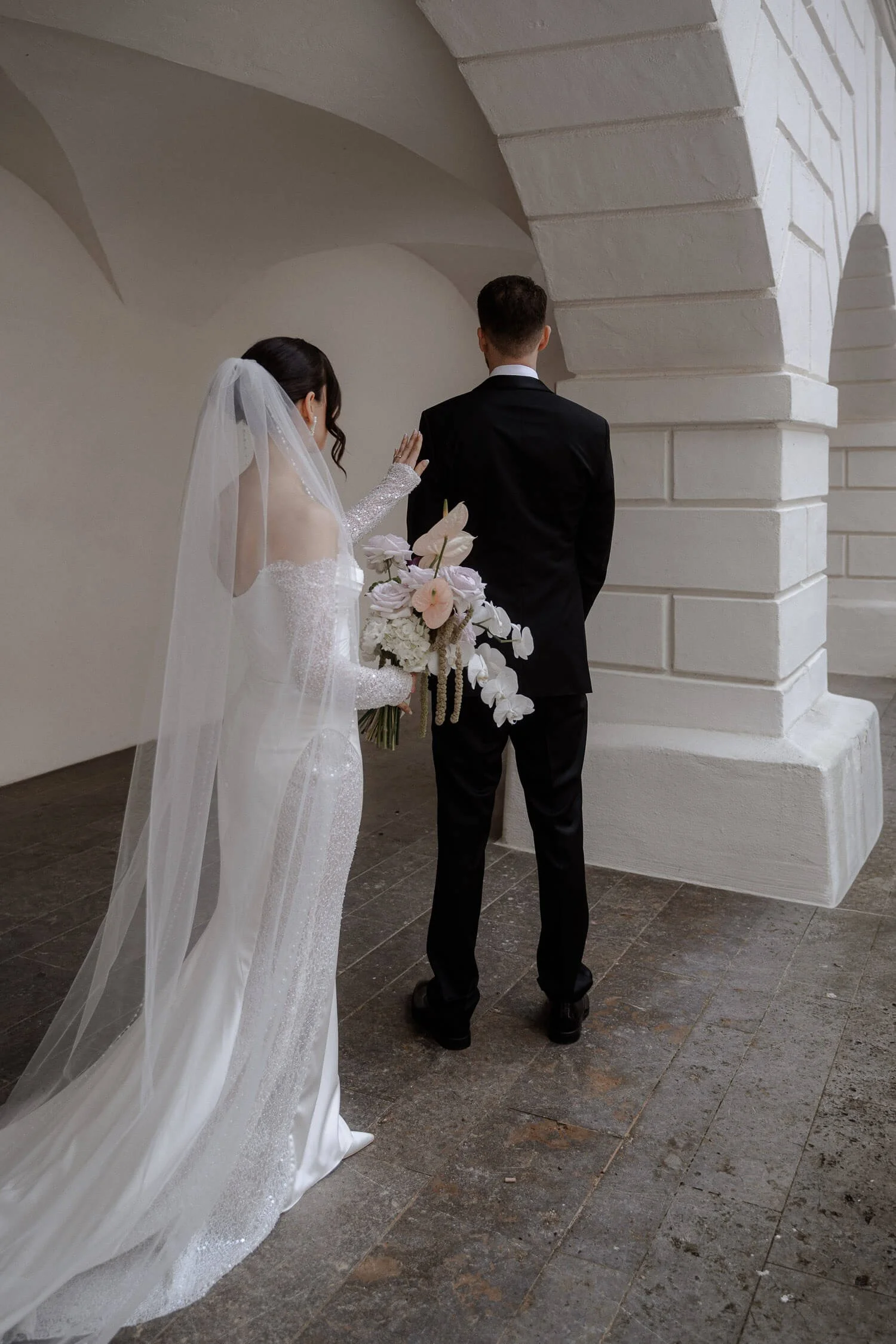 Braut nähert sich ihrem Bräutigam für den First Look.