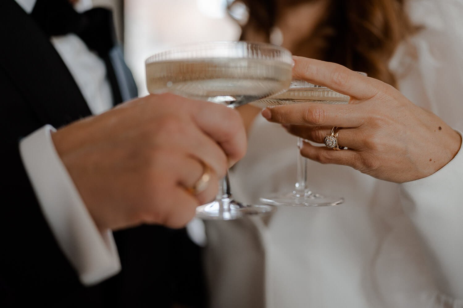 Nahaufnahme eines Hochzeitspaares beim Anstoßen mit Champagnergläsern.