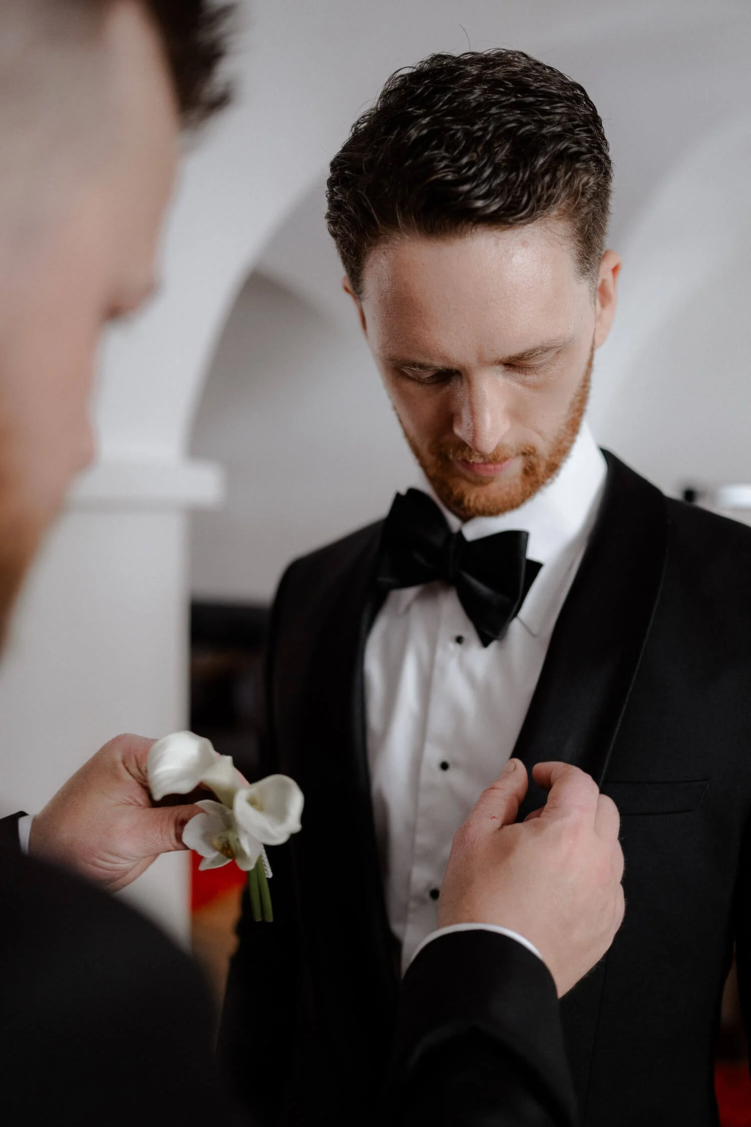 Bräutigam bekommt Ansteckblume vor der Trauung.