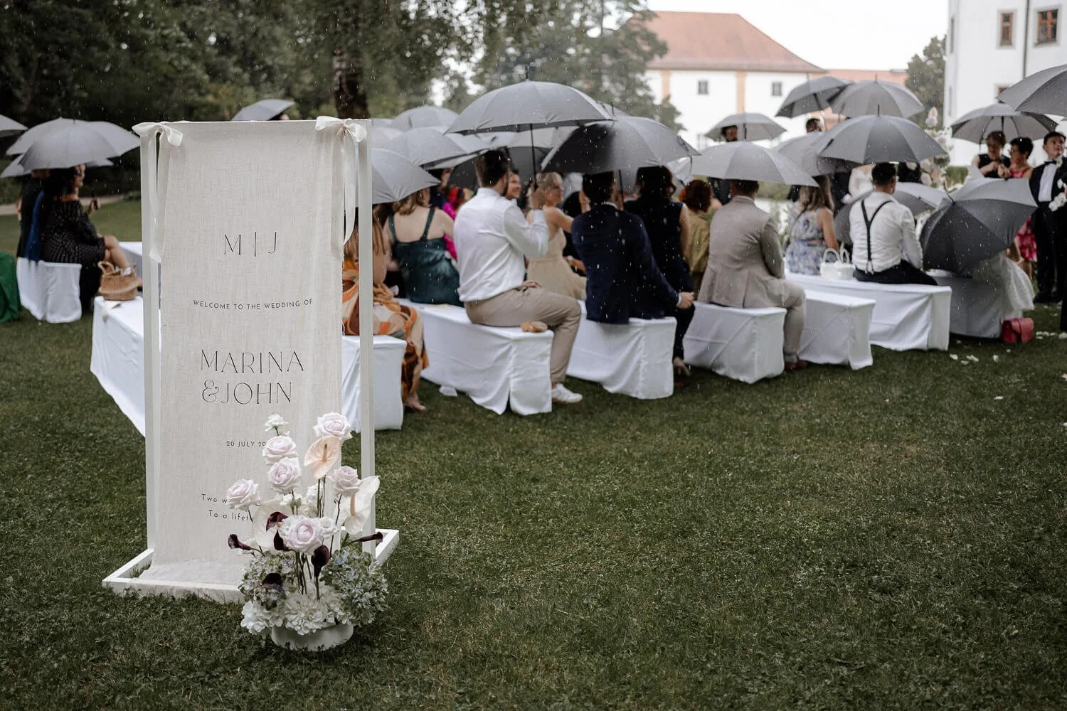 Hochzeitsgäste mit Regenschirmen bei freier Trauung im Regen