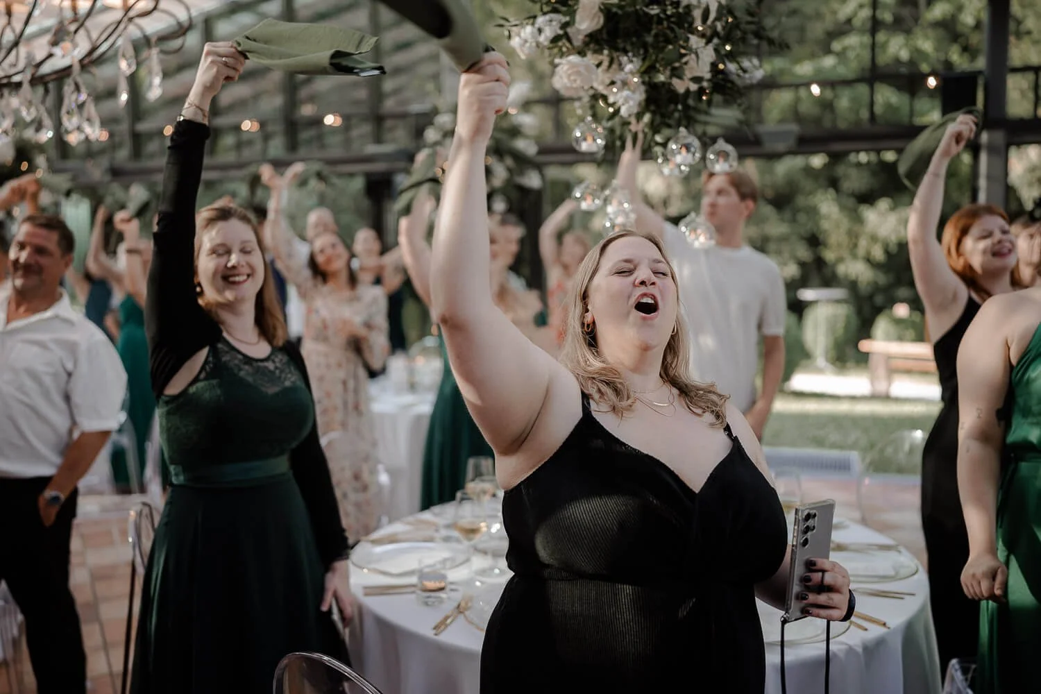 Hochzeitsgäste feiern mit Servietten in der Orangerie vom La Villa Starnberg