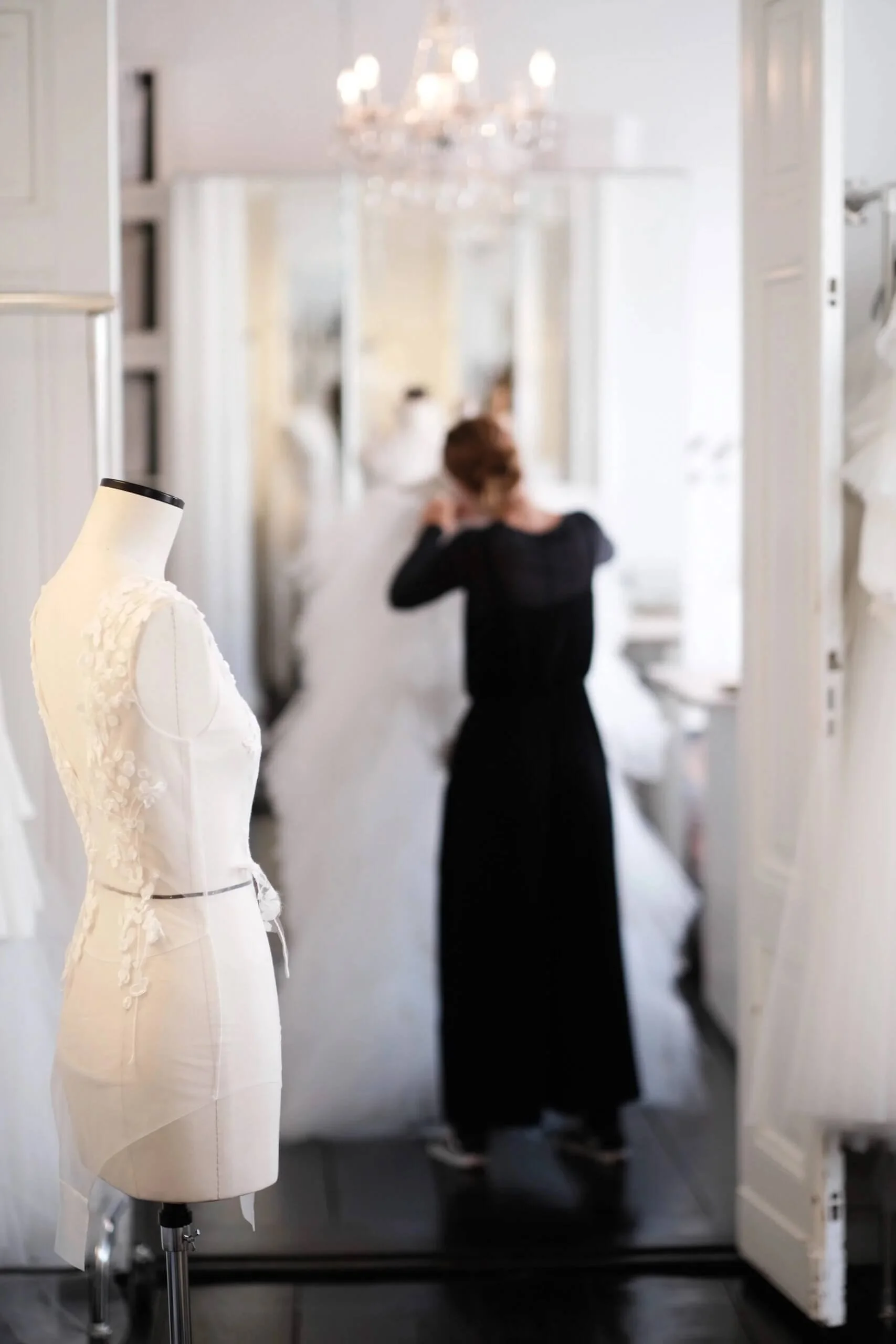 Brautmodengeschäft München: Schneiderin steckt Brautkleid ab, Kleidpuppe im Vordergrund