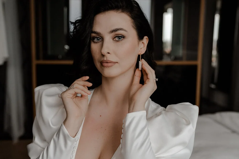 Bride adjusting pearl earring in bridal suite