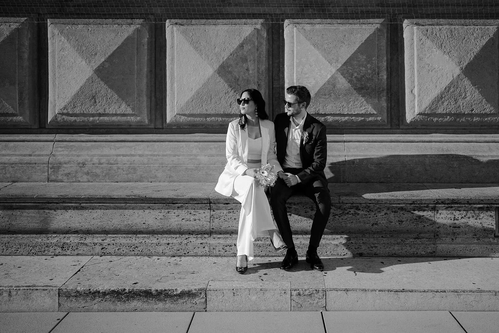 Brautpaar sitzt auf Steintreppe nach der standesamtlichen Trauung