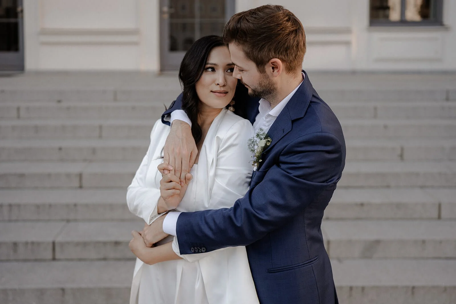 Brautpaar umarmt sich vor Treppe – moderne Hochzeitsfotos München