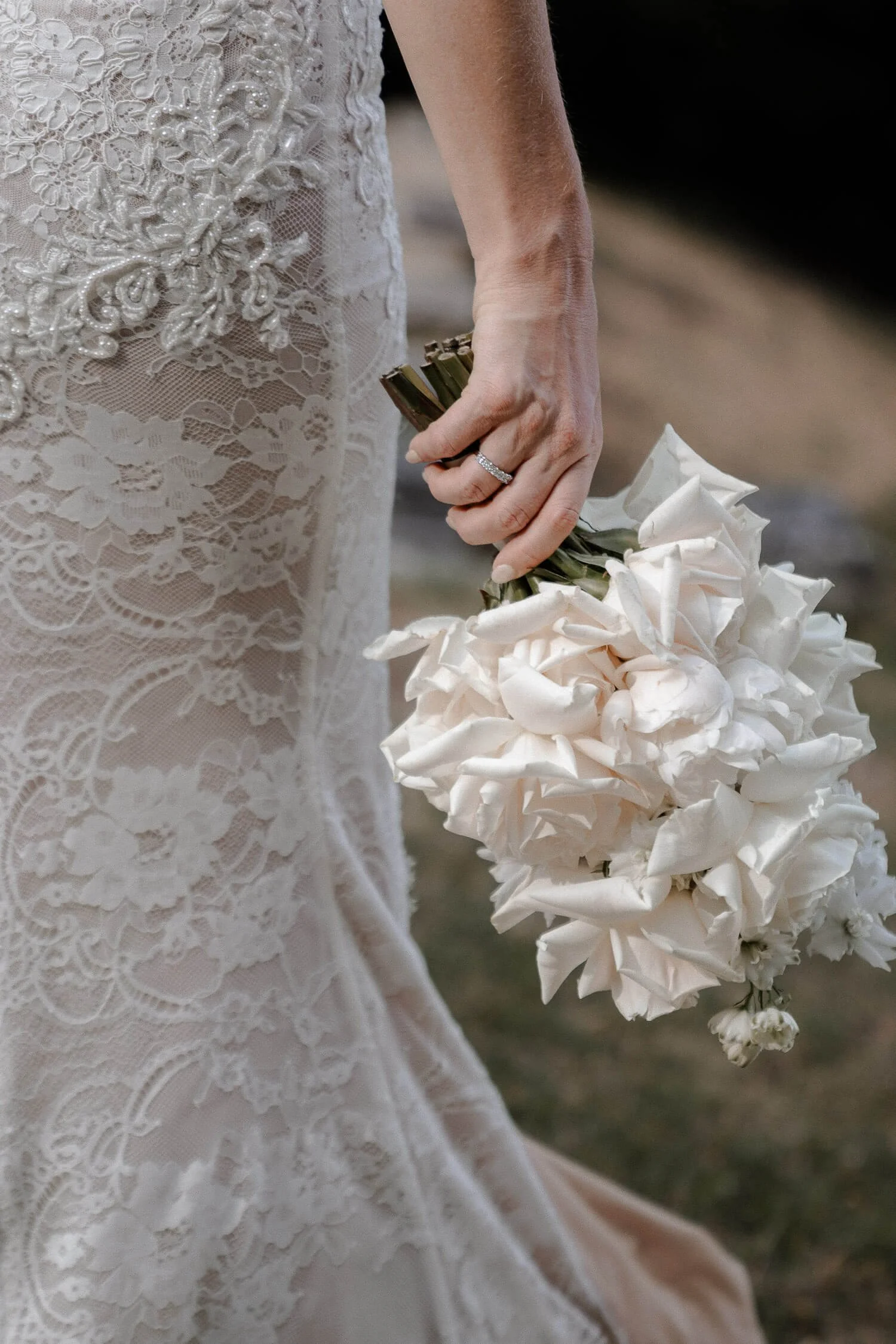 Braut hält weißen Strauß vor dem Kleid