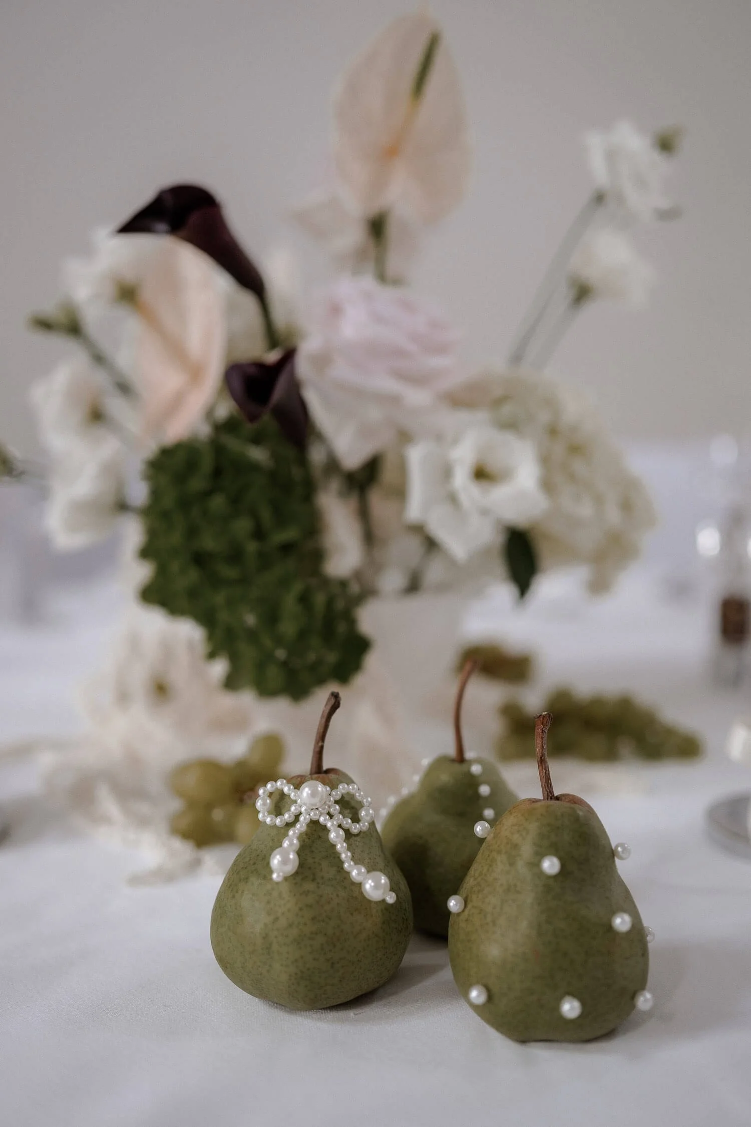 Hochzeitsdeko mit Birnen und Perlen auf Tisch.