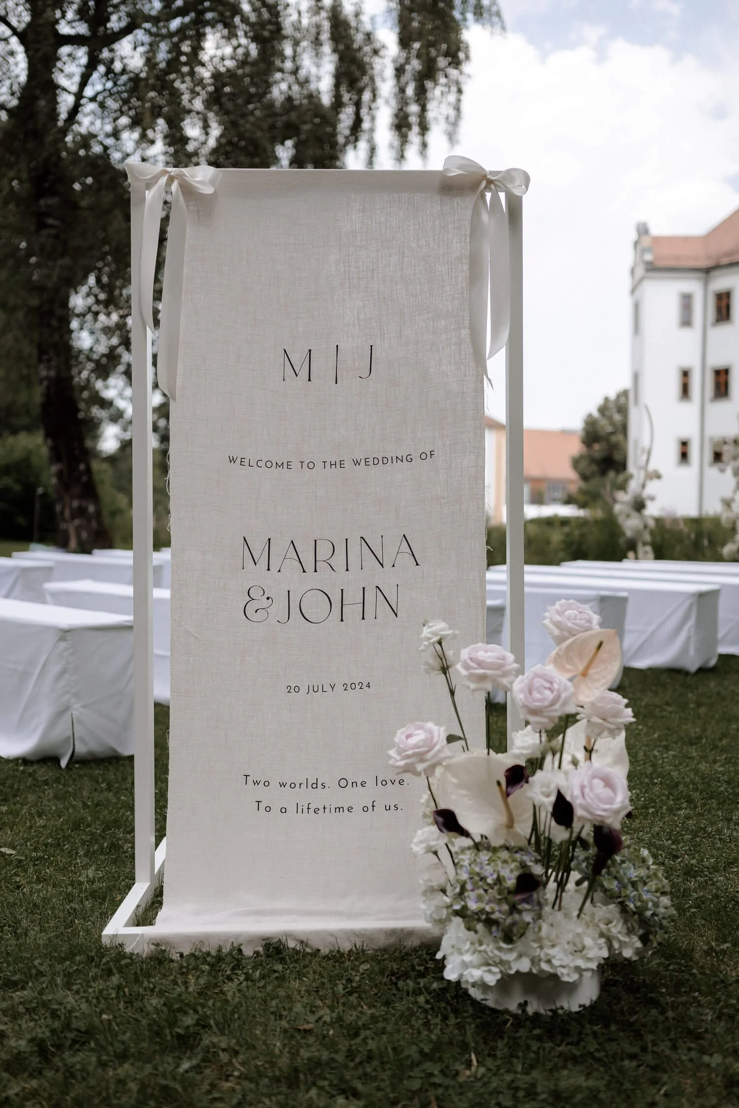 Hochzeitsschild mit Blumenarrangement auf Wiese.