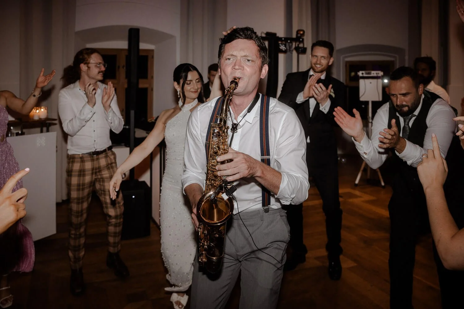 Saxophonspieler auf Hochzeitsparty in München, Gäste feiern ausgelassen