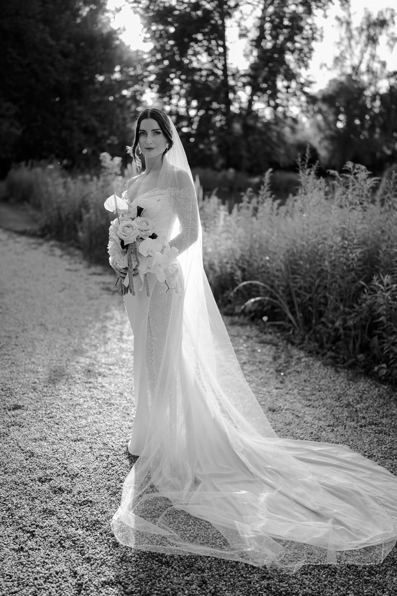 Braut im Sonnenlicht mit Schleier und Brautstrauß