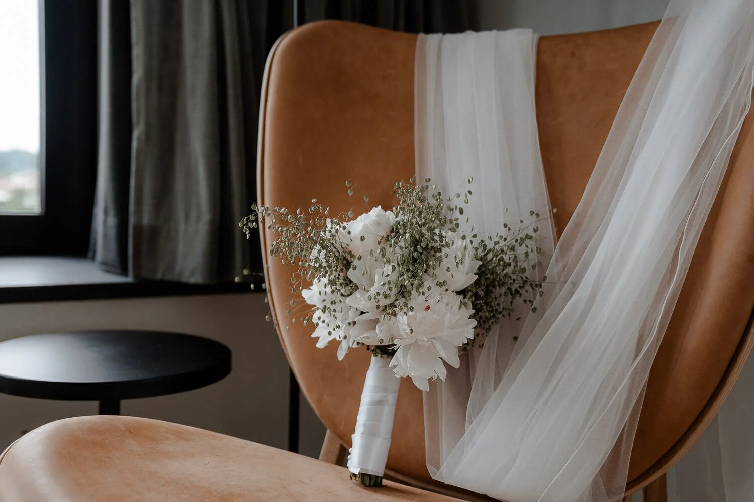 Brautstrauß &amp; Schleier auf Ledersessel im andaz munich schwabinger tor