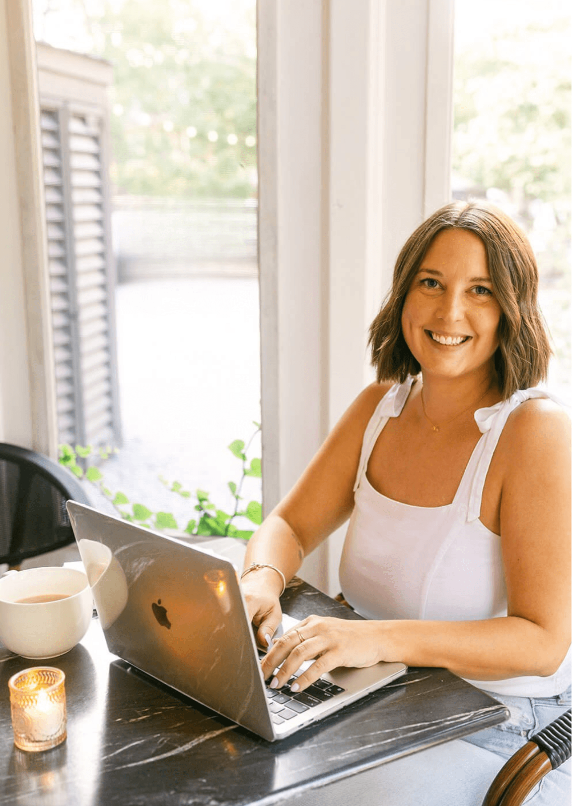 Polly, a website copywriter, typing on laptop and smiling at camera