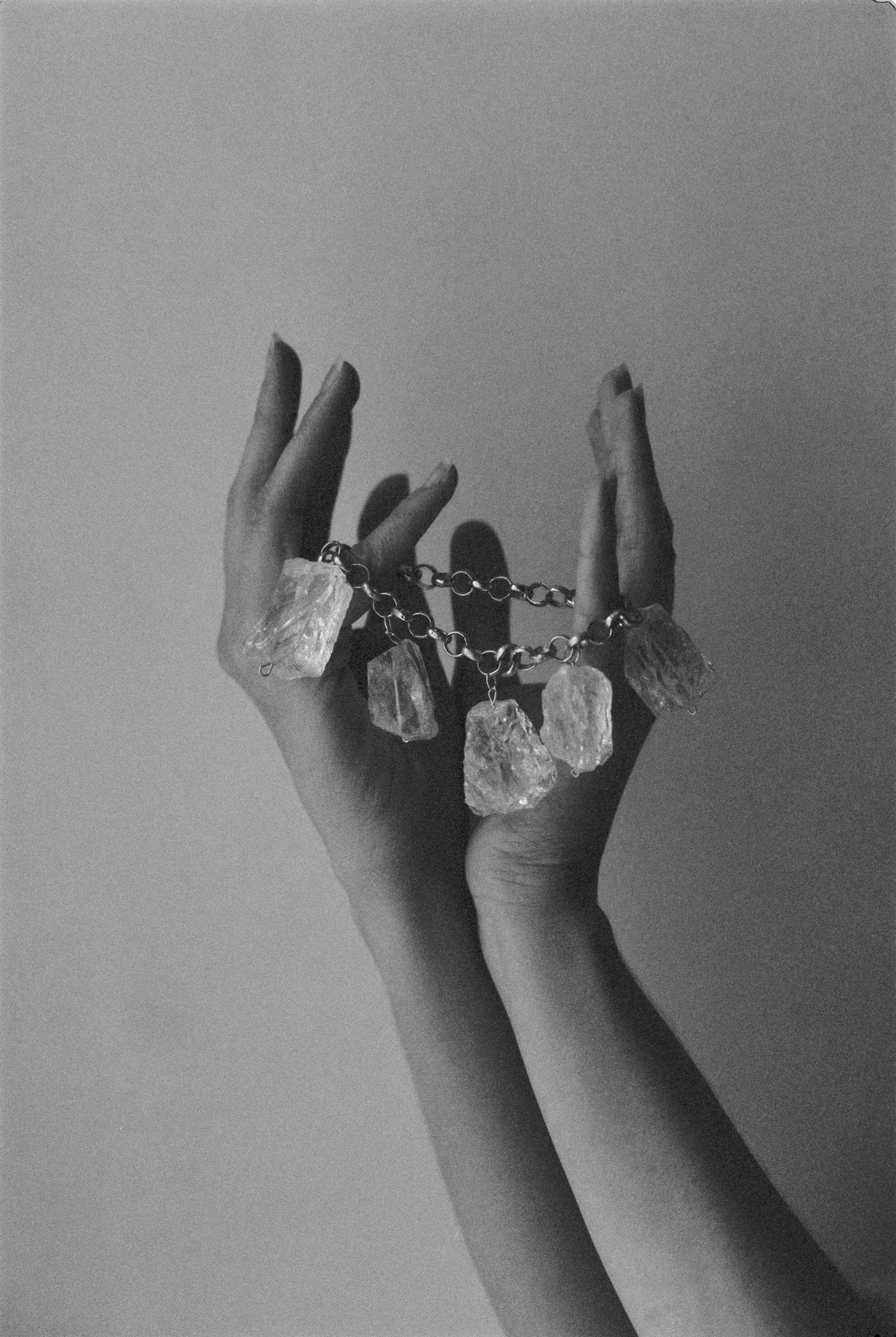 Hands holding a chain with large crystal stones.