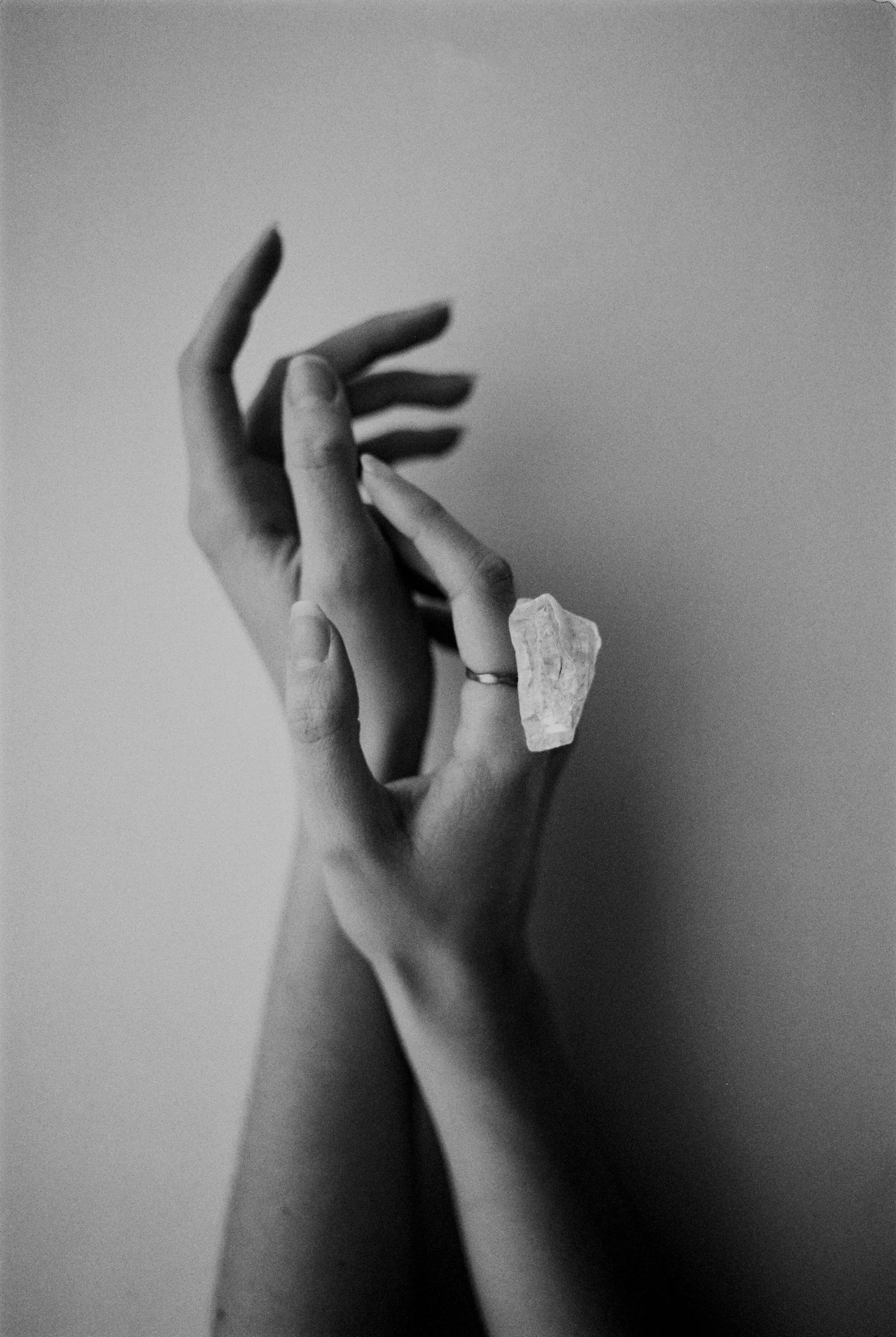 Black and white photo of two hands, one wearing a large crystal ring.