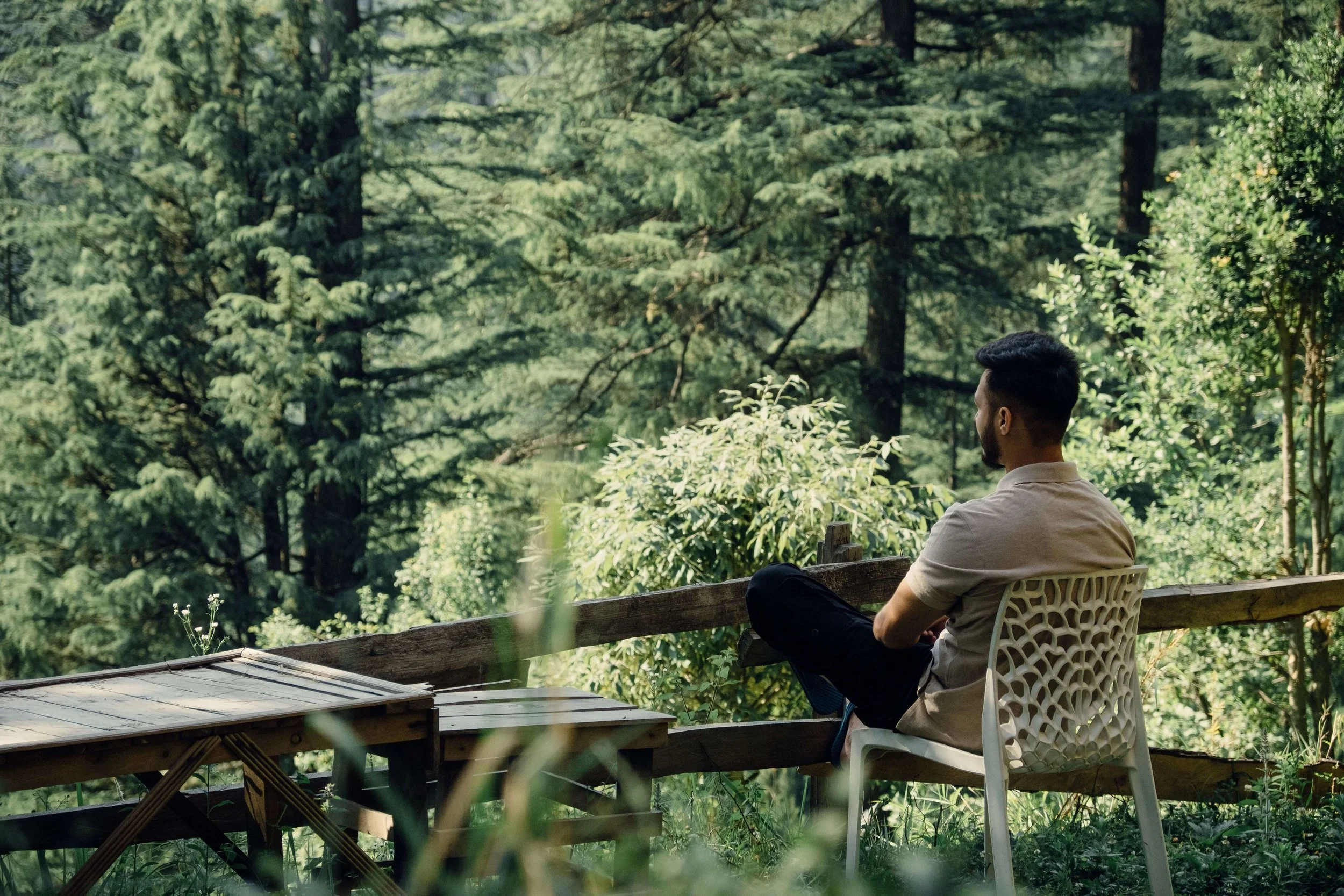 Person sitting peacefully in a chair overlooking the forest, representing rest and reflection while healing from adverse religious experiences in St. Paul, MN, with an LGBTQIA2S+ therapist in Minneapolis, MN.