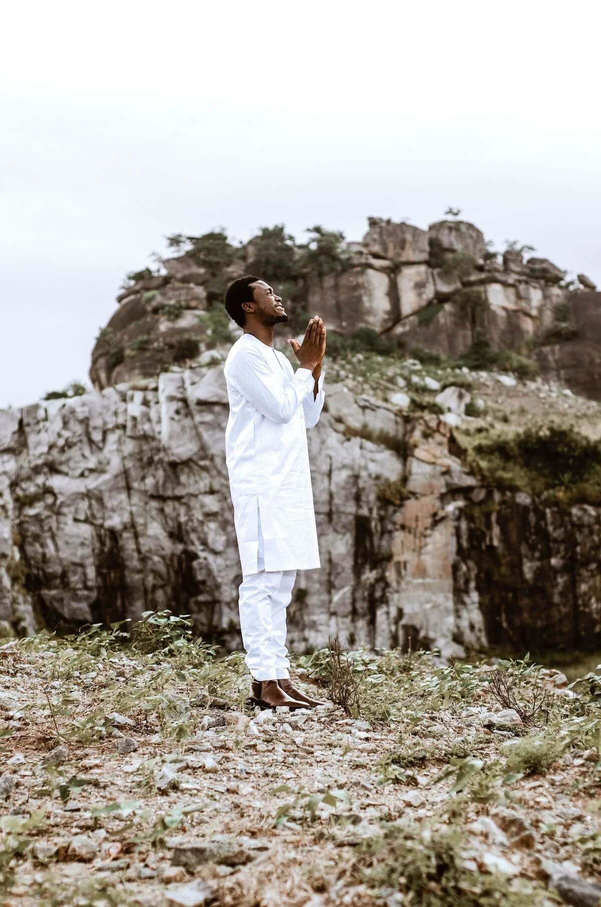 Man standing outdoors with hands clasped in prayer, looking upward, representing the journey of reclaiming faith through religious trauma therapy with a religious trauma therapist in St. Paul.