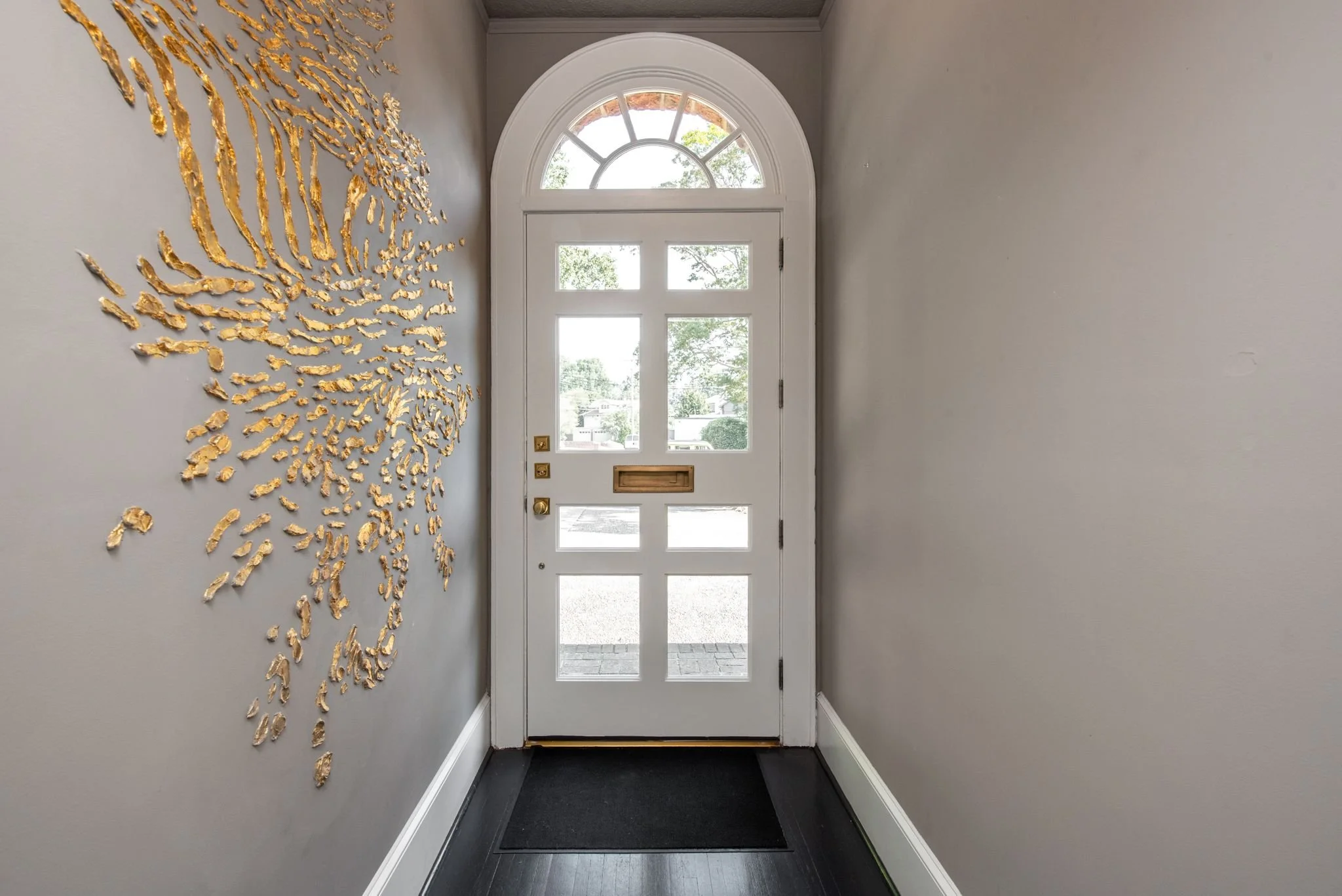 An in terror shot of a front door, painted white, with antique brass hardware