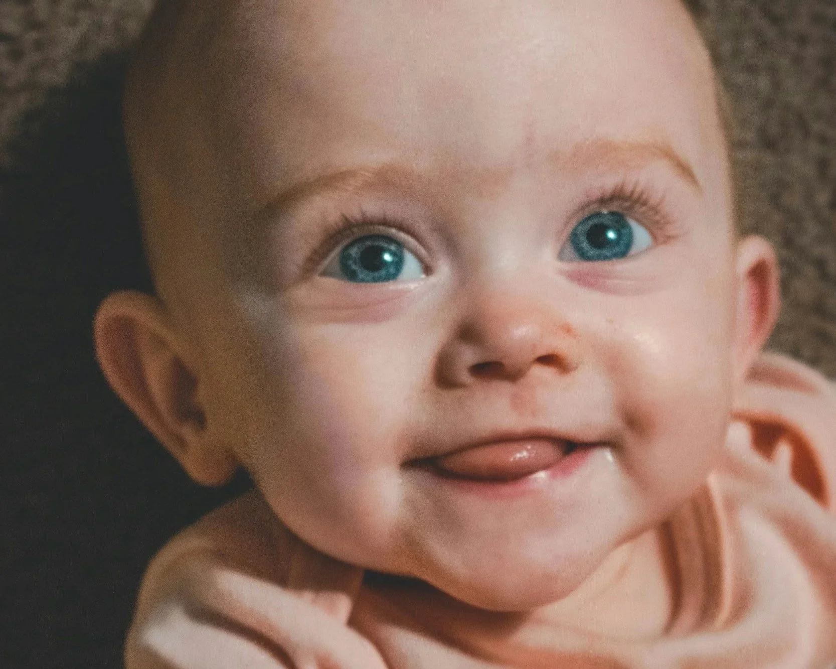 Baby's face with bright blue eyes and tongue slightly poking out