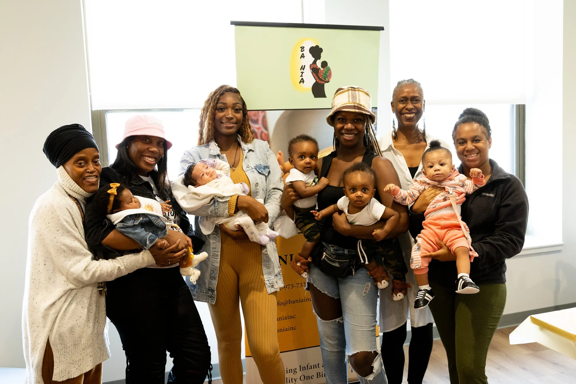 a group photo of Black women smiling and holding babies