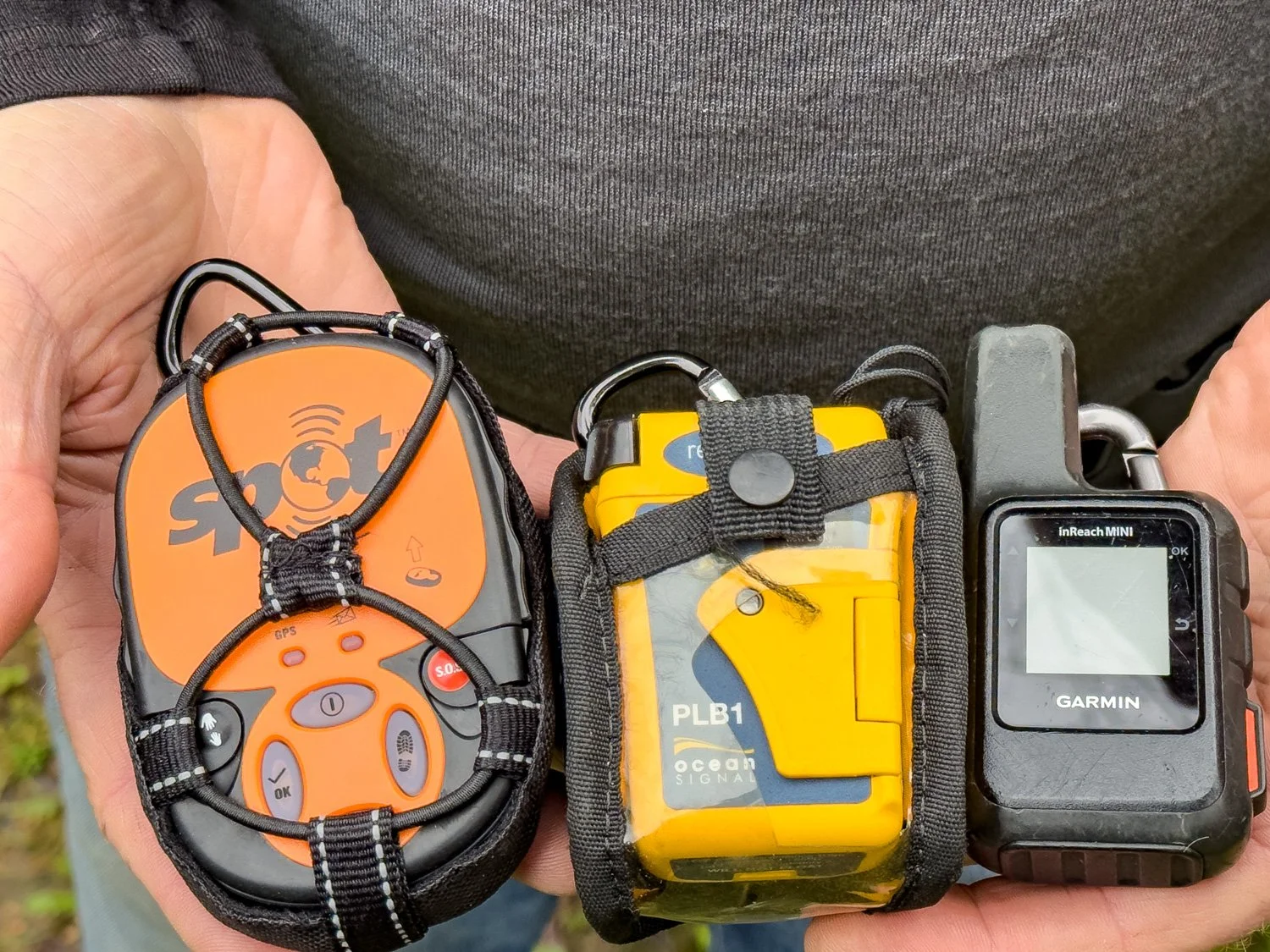 man holding Spot, PLB and Garmin Mini Inreach in his hands