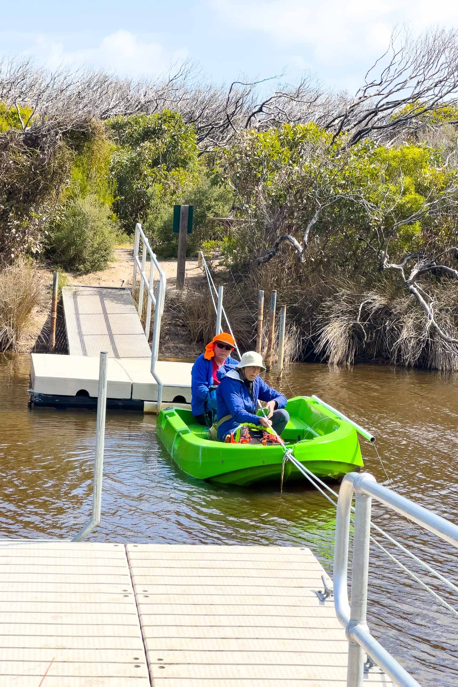 two hikers in small dingy one pulling on rope to cross the small river