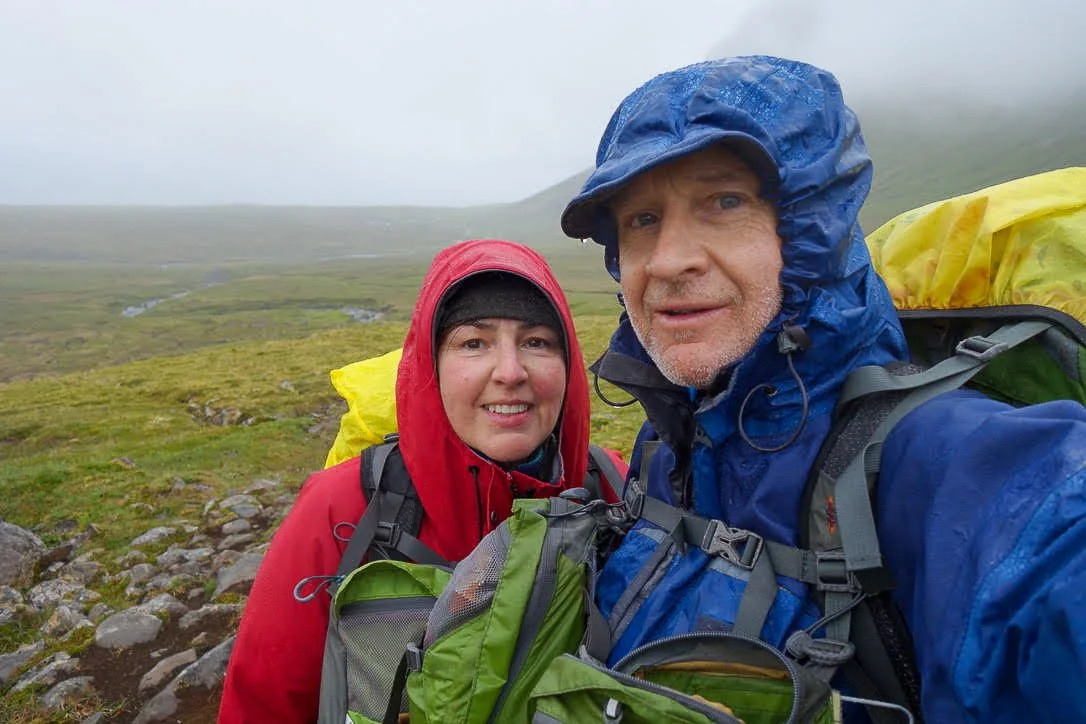 two hikiers in rain gear one red jacket the other blue