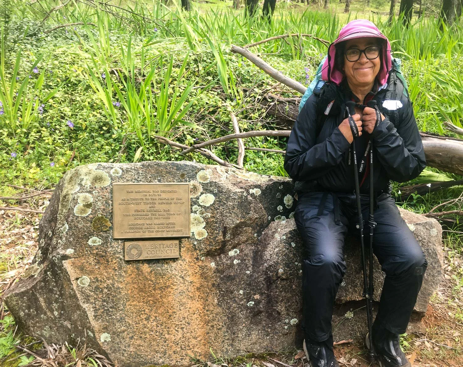 hiker sitting on rock in full rain gear pants have a patch on one knee