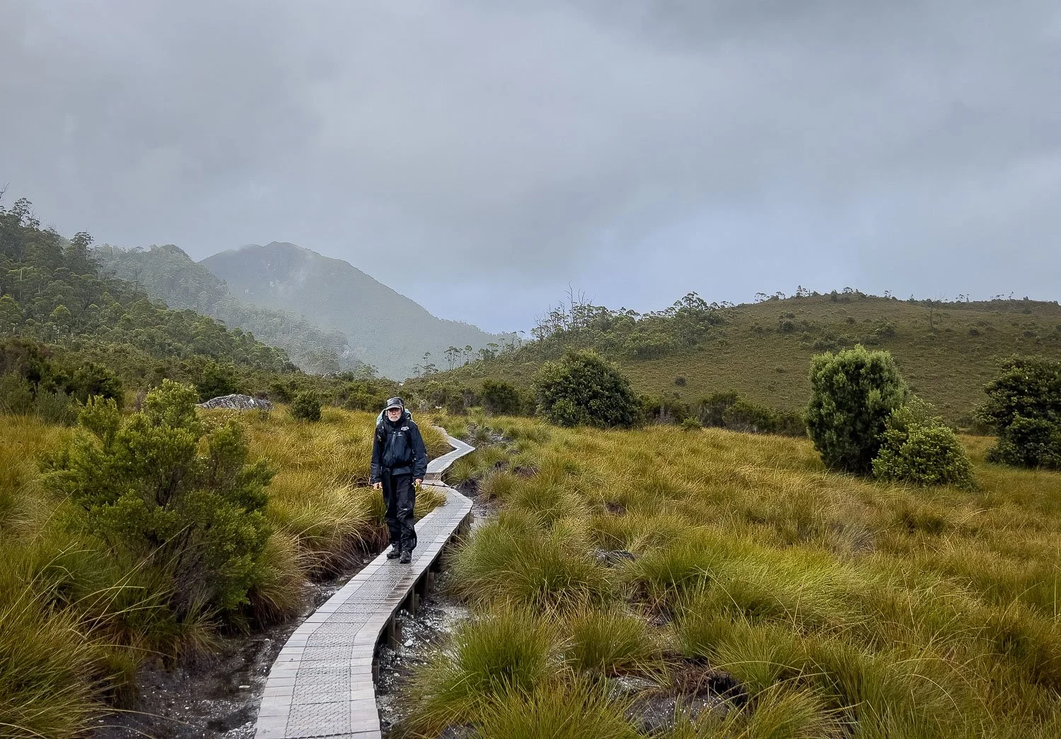 hiker in full raingear on duckboards walking in misty rain