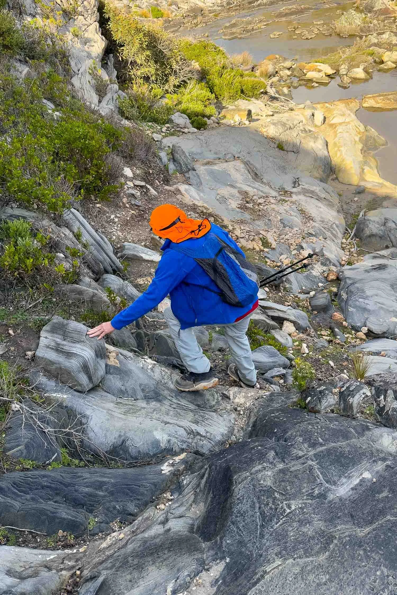 hiker with day pack scrambling down very short section of steep rocky track