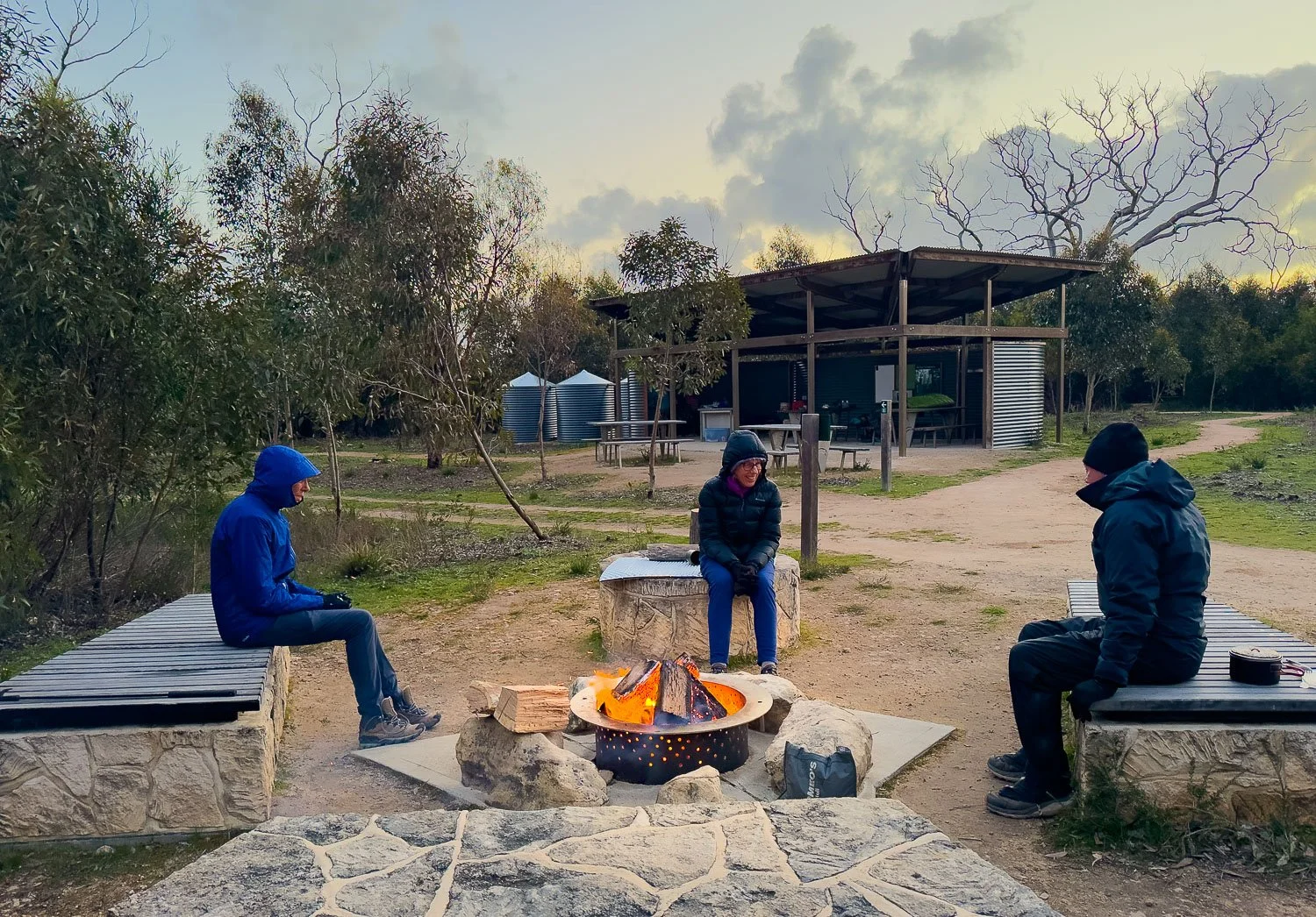 three hikers sitting around a camp fire near Grassdale Hut