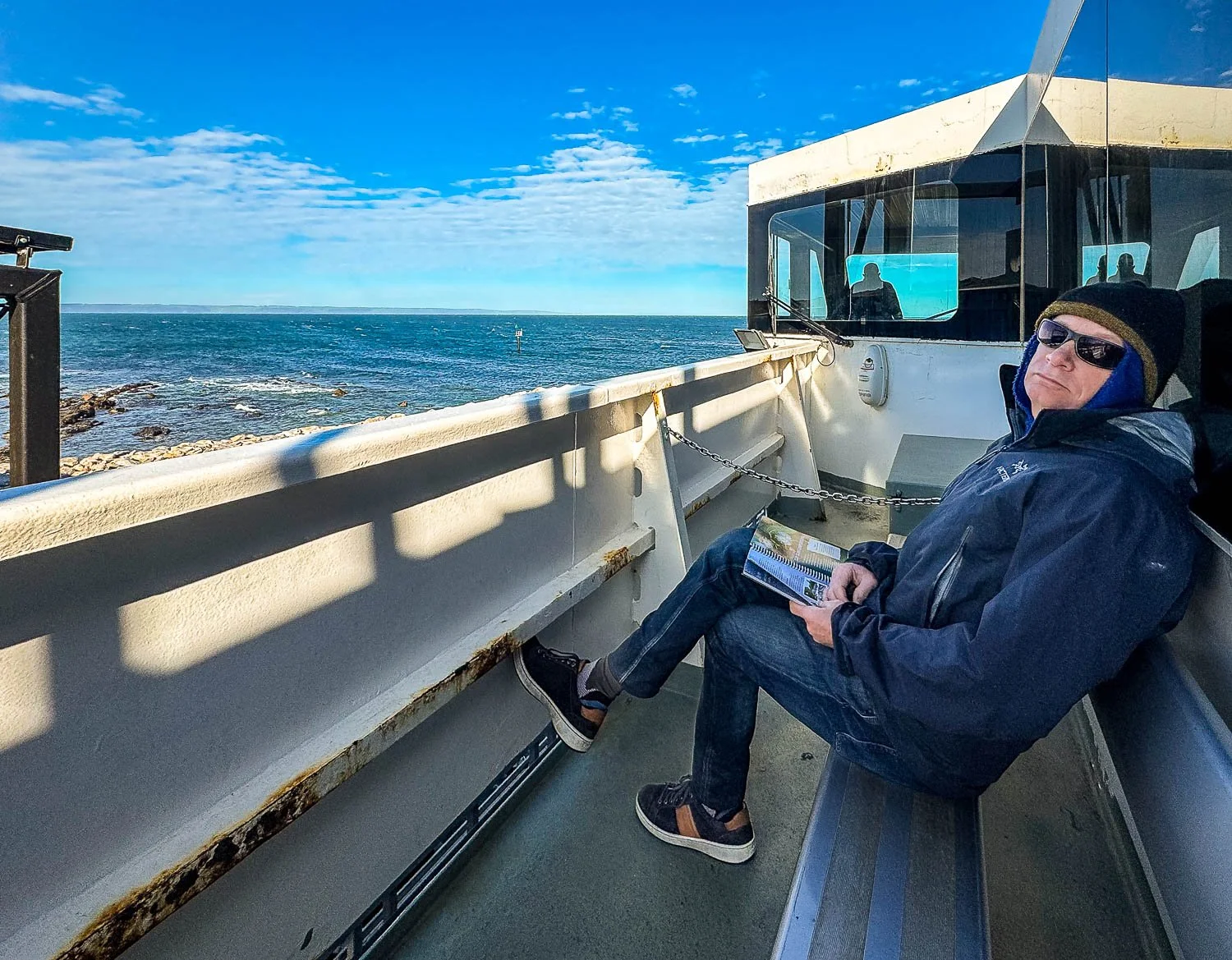 man with map book on lap lying back lazily against seat on ferry boat