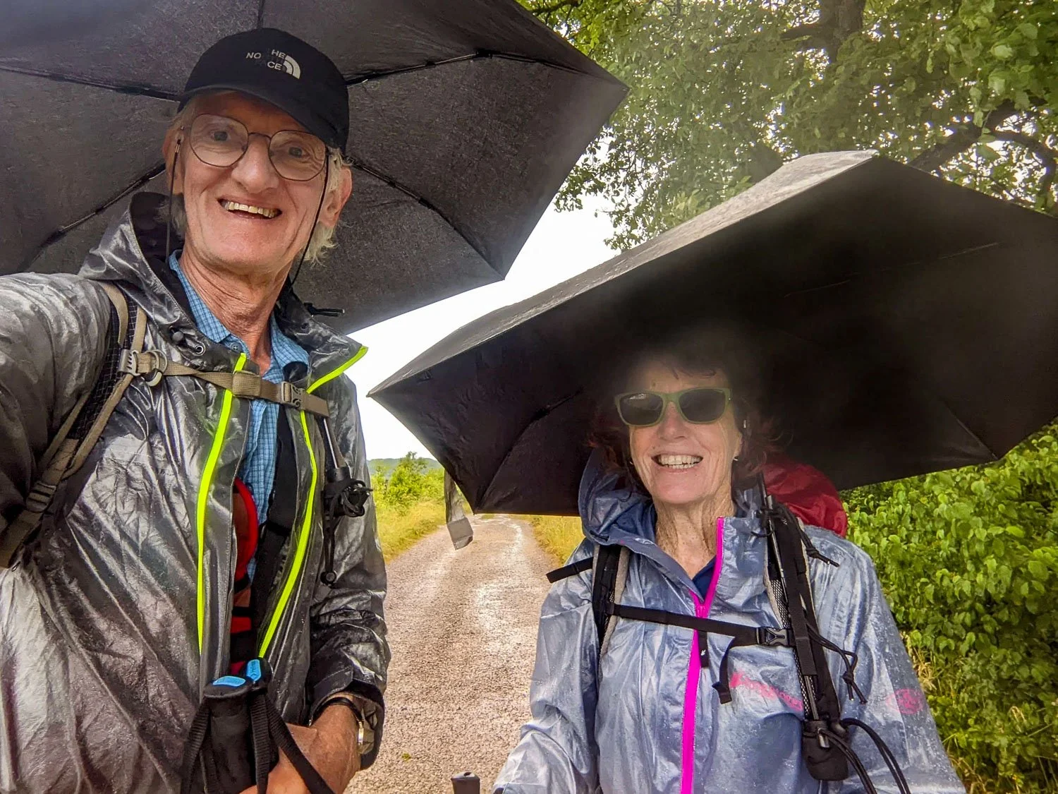 smiling hikers under their umbrellas in light rain