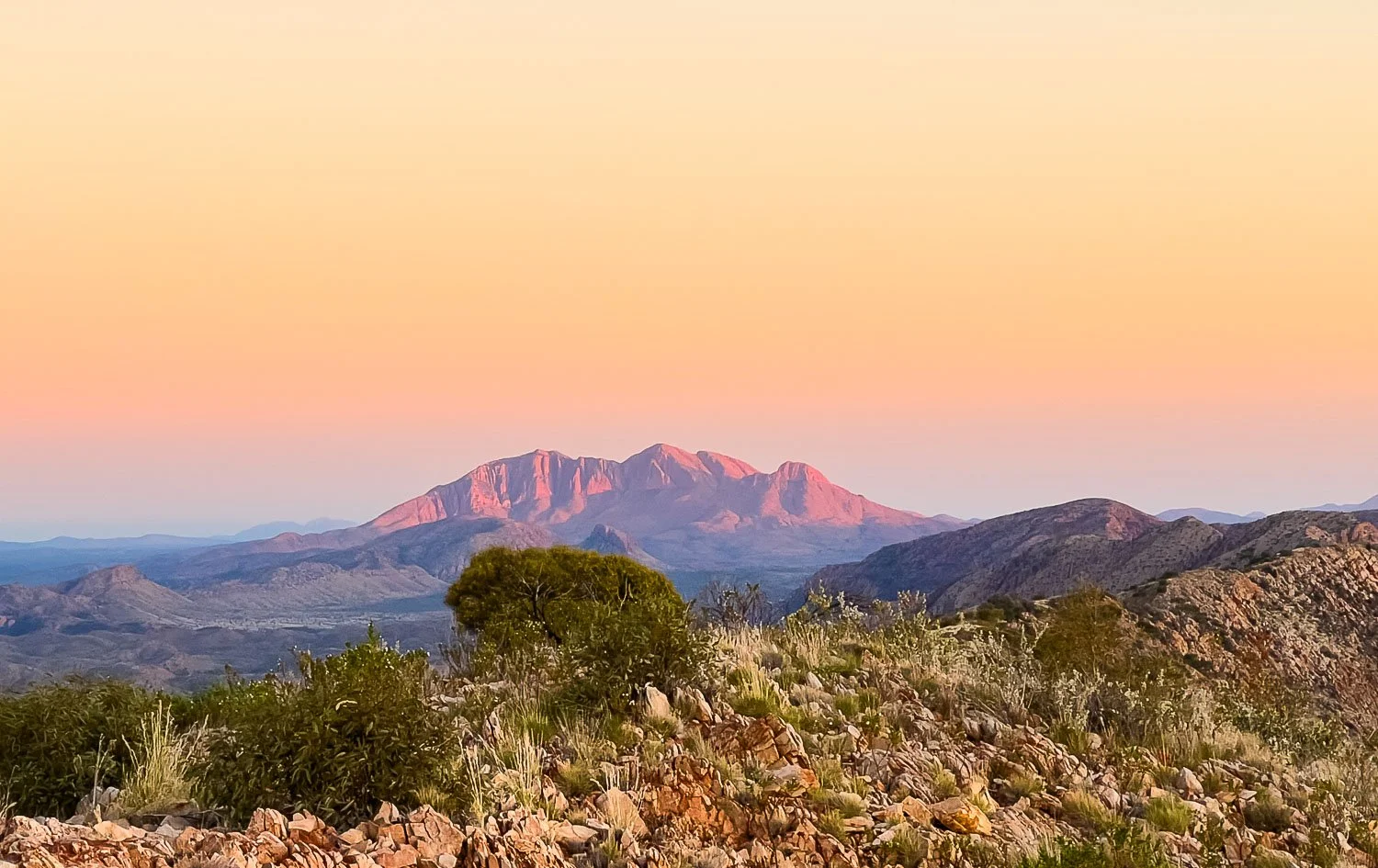 Mount Giles in distance is glowing orange under soft morning light