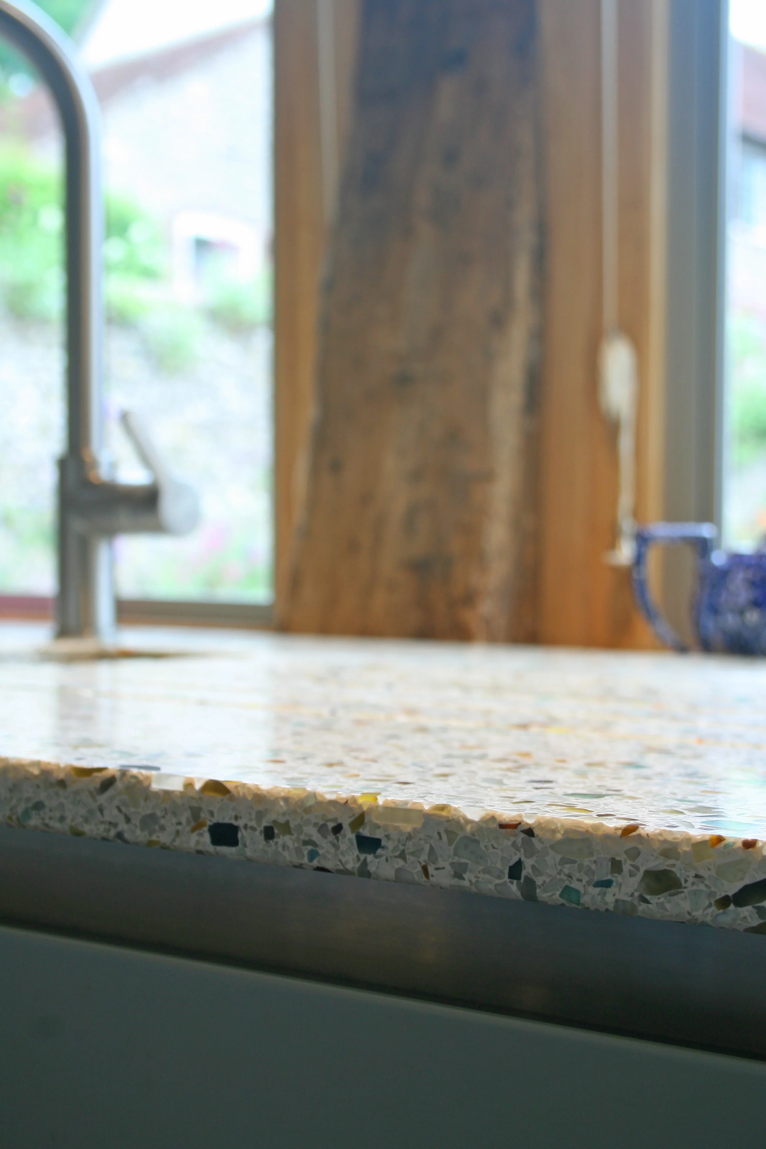 Close up view of colourful and hard wearing worktops in a converted barn in East Sussex for architect client, Including stainless steel under mounted sink and drainange grooves