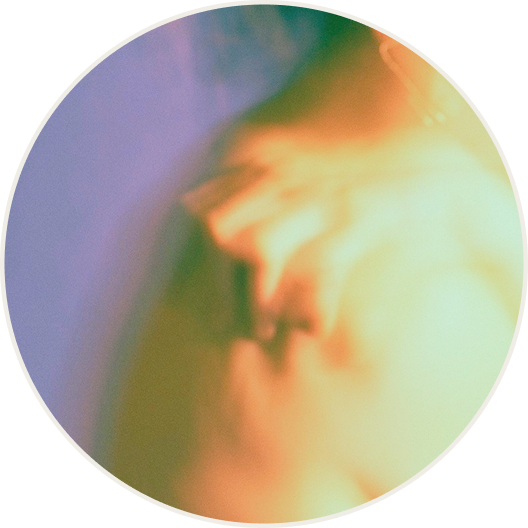 a women leaning over with her hand clenching her shoulder against a purple background, the image is slightly blurred