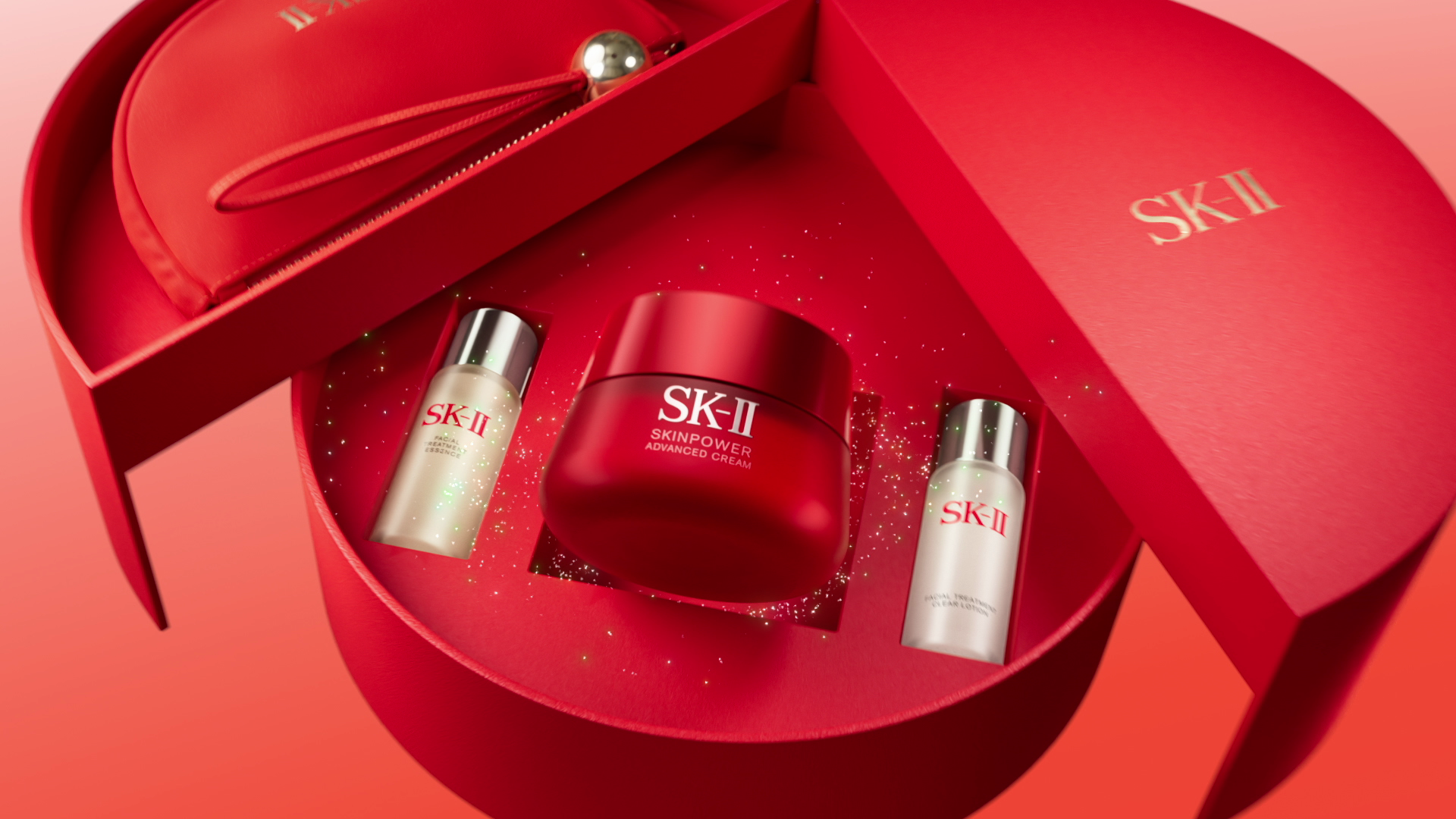 A red Sk-II skincare gift set with a jar of advanced cream, two bottles of facial treatment essence, and a small red pouch, arranged inside an open red heart-shaped box with a matching lid.