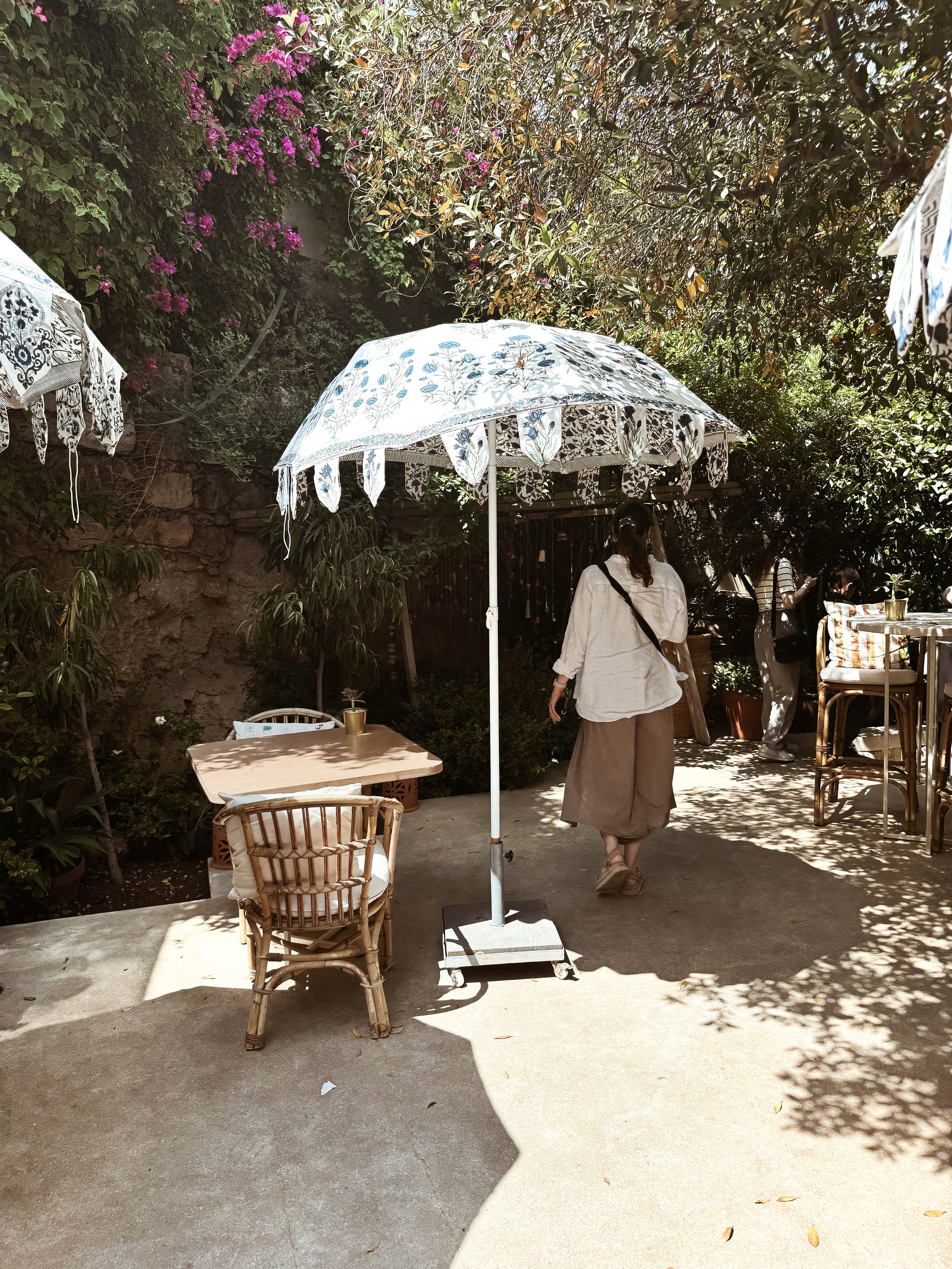 woman-walking-under-sun-umbrealla-cafe-seatingJPG.jpg