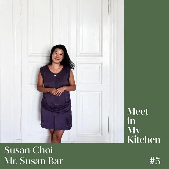 A woman in a purple dress standing in front of a white door, smiling, with a green background on the right side that has white text reading 'Meet in My Kitchen' and information about Susan Choi and Mr. Susan Bar.
