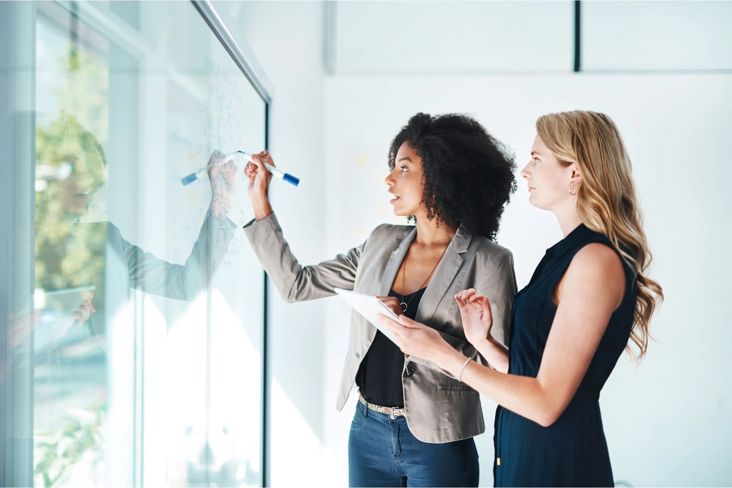 Two professional women collaborating at a whiteboard