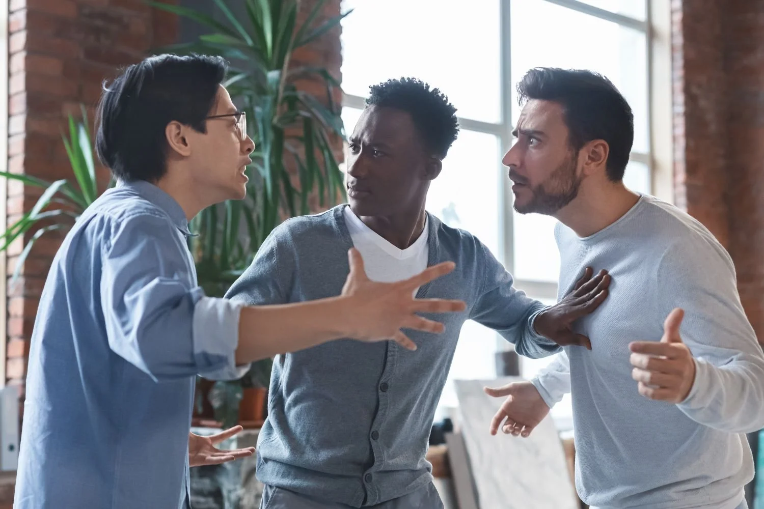 Three men engaged in an argument with one trying to mediate