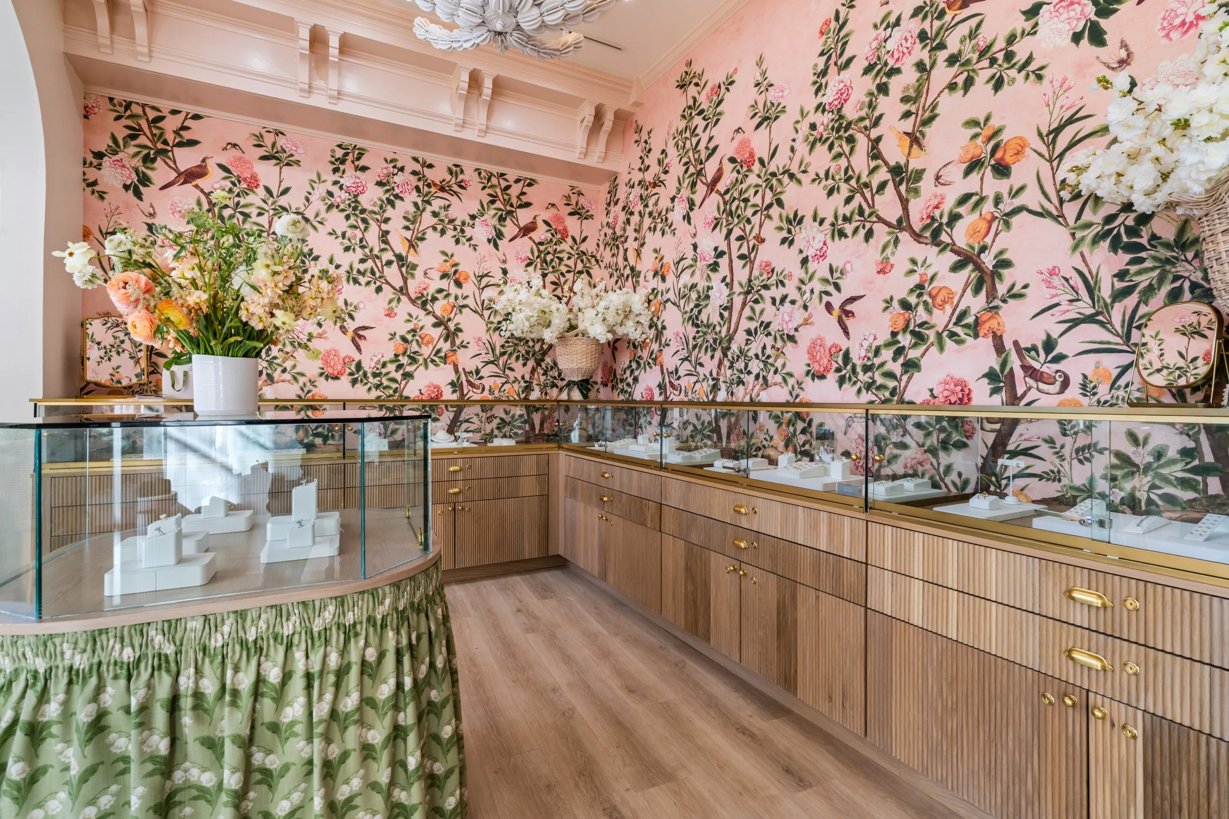 Interior of a jewelry store with floral wallpaper, wooden display cabinets, and glass jewelry cases.