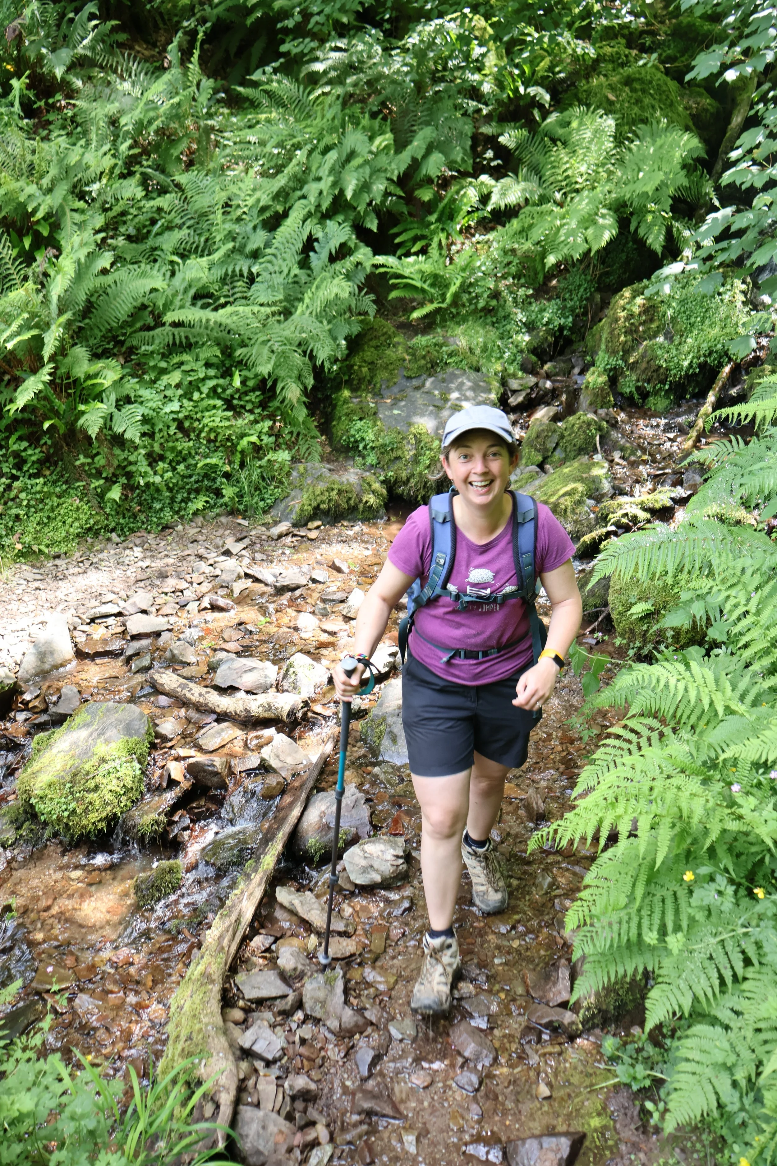 Happy looking walker crossing a stream in the woods on the South West Coast Path