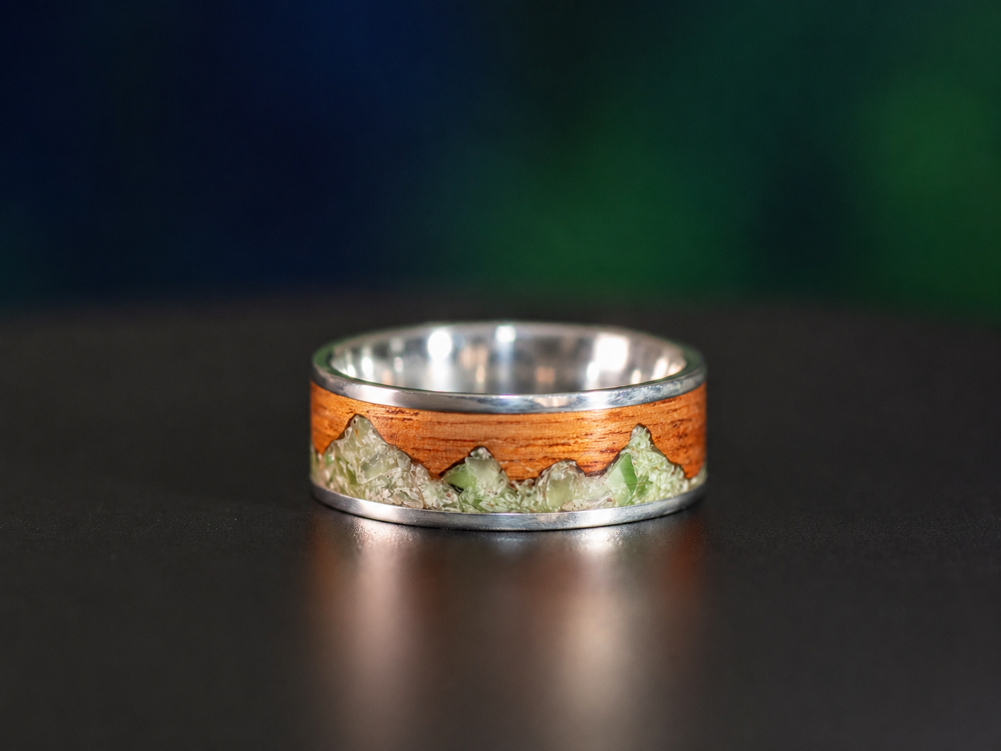 Handmade sterling silver ring featuring a green jade mountain inlay set into natural tineo wood.