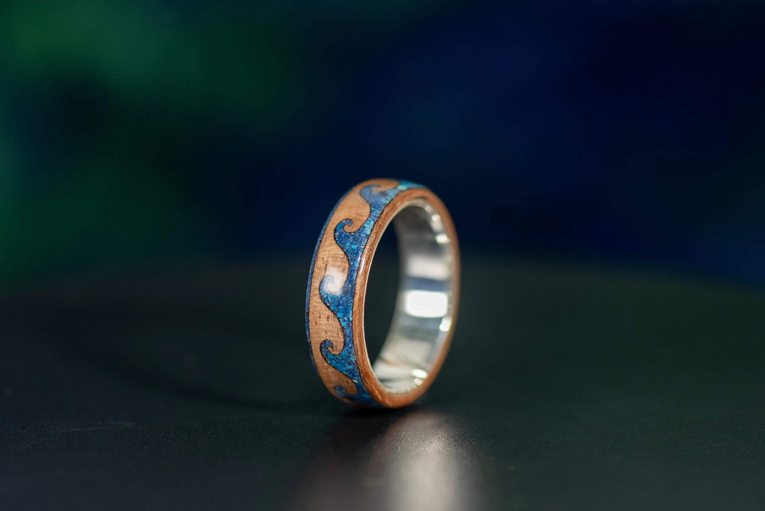 Ocean inspired walnut ring with blue lapis lazuli and shattuckite wave design wrapping around the band.