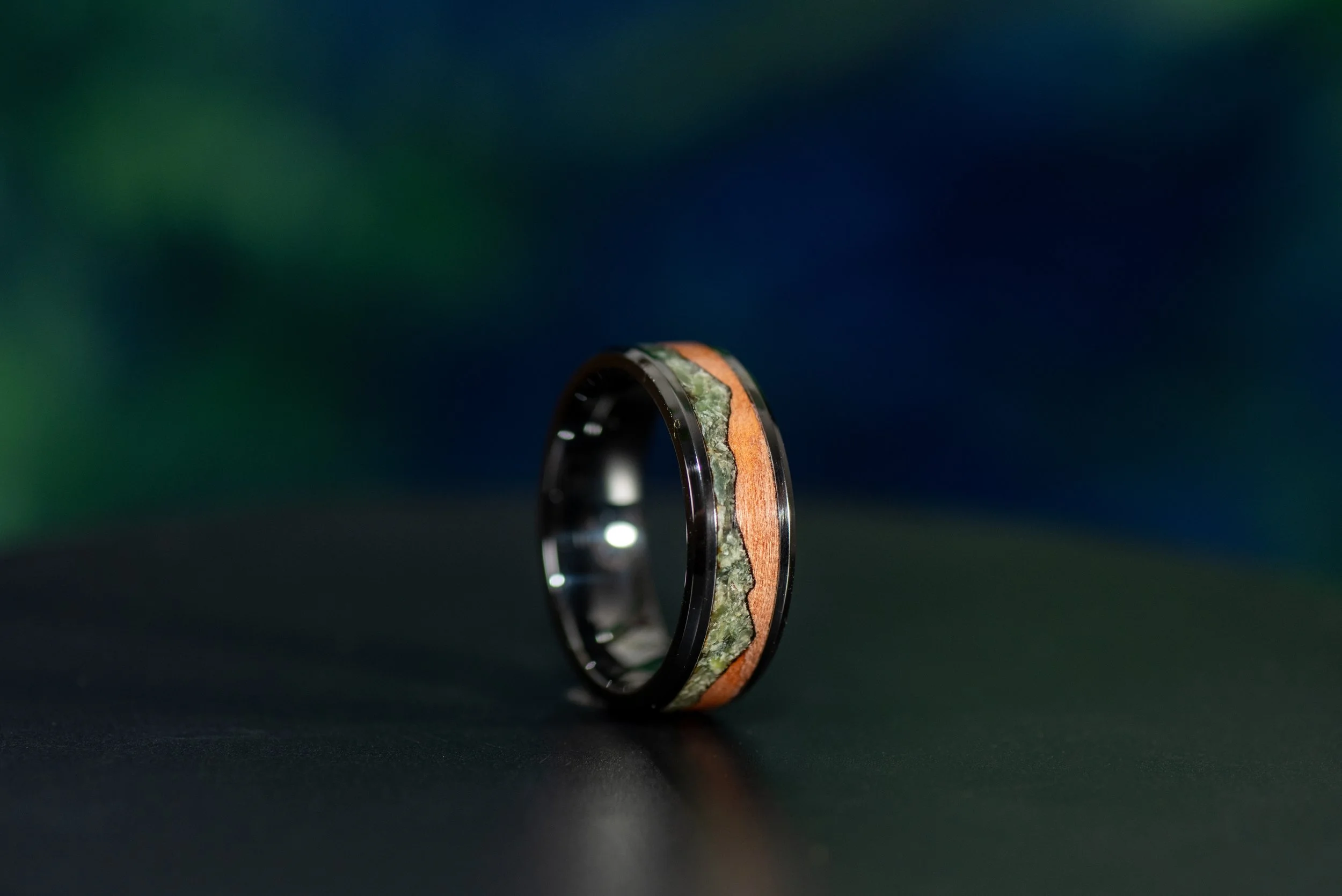 Nature inspired black ceramic wedding band with jade mountains inlaid into tineo wood.